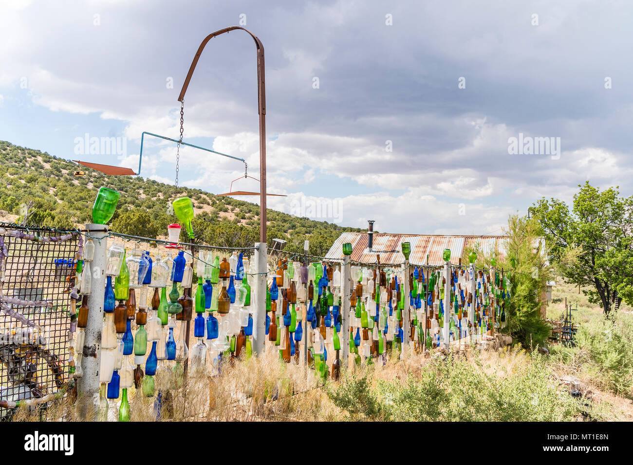 Hanging multicolored glass bottles make up a unique fence in Golden, New Mexico. Stock Photo