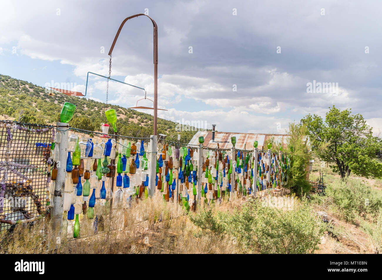 Hanging multicolored glass bottles make up a unique fence in Golden, New Mexico. Stock Photo