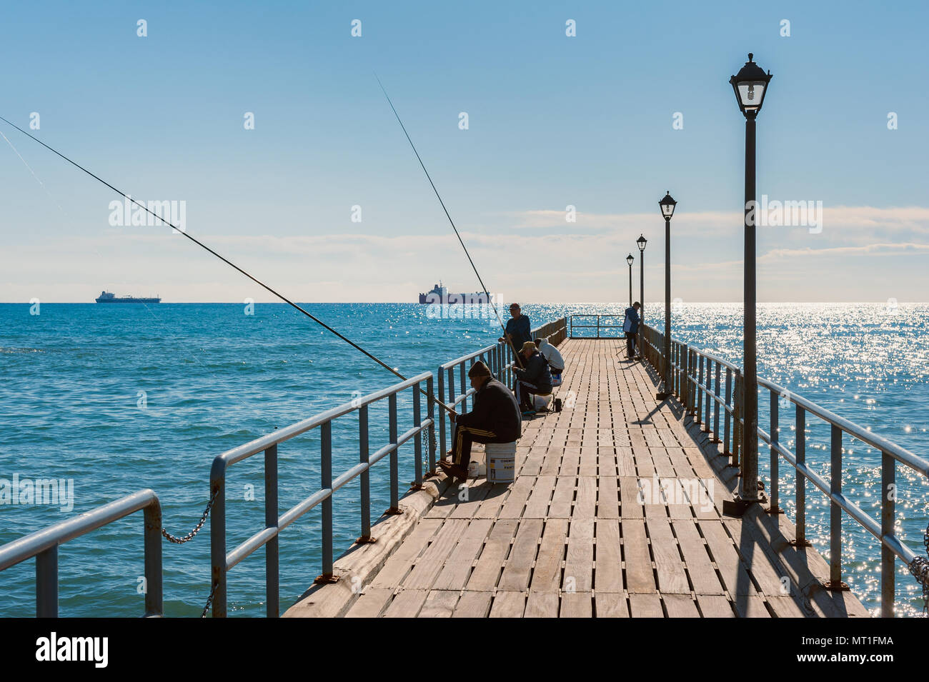 Men Fishing on Jetty in Limassol, Cyprus. Cyprus is an Eurasian island country in the Mediterranean Sea and southeastern most part of Europe. Stock Photo
