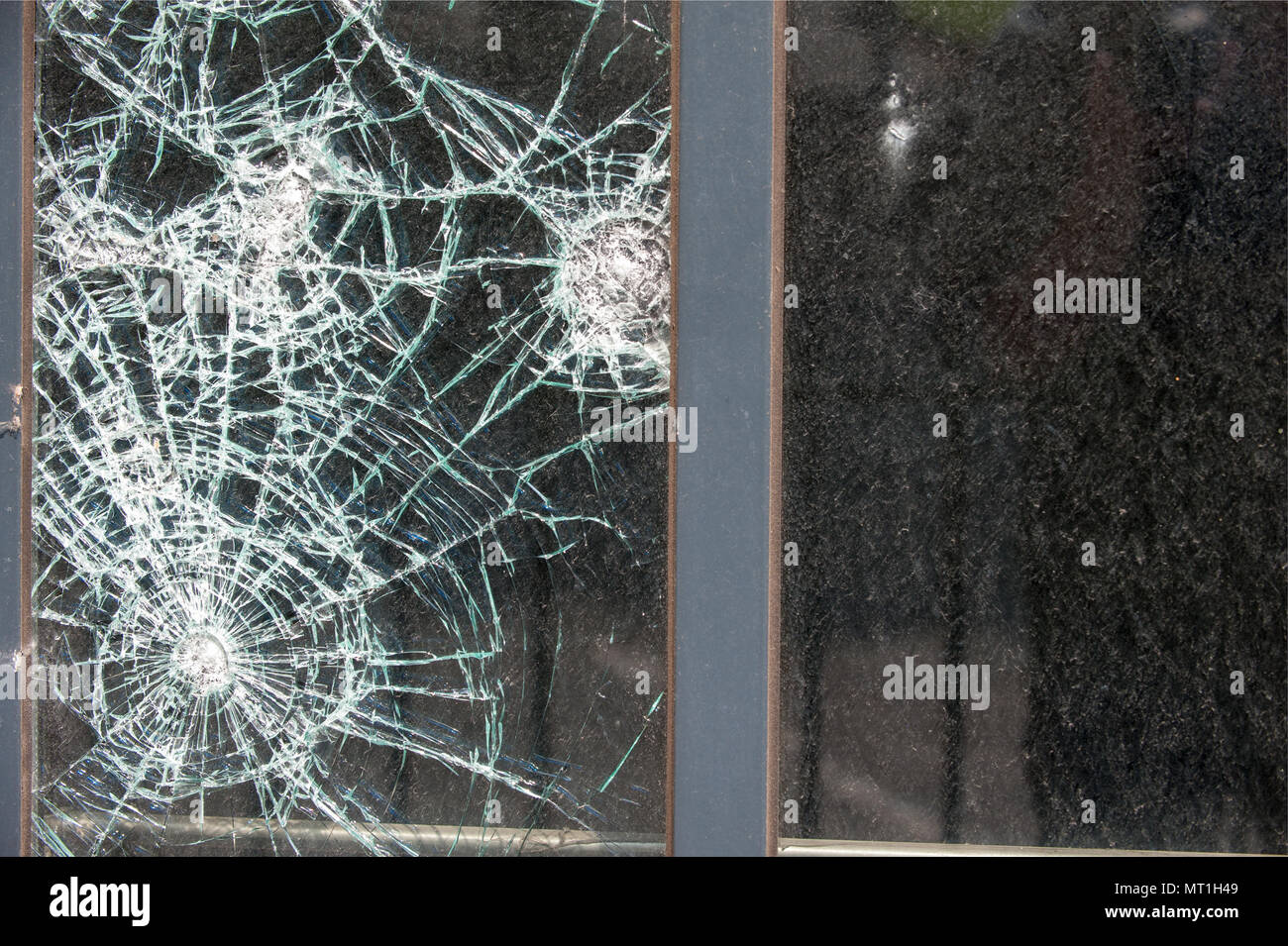 Close-up of a shattered glass window with multiple impact points and spiderweb cracks, highlighting vandalism or accidental damage to property Stock Photo