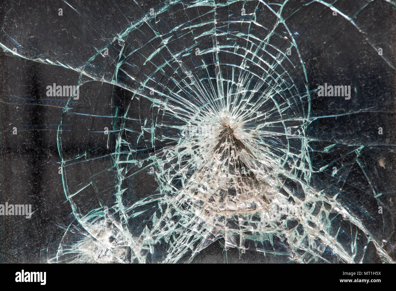 Close-up of a shattered glass window with multiple impact points and spiderweb cracks, highlighting vandalism or accidental damage to property Stock Photo
