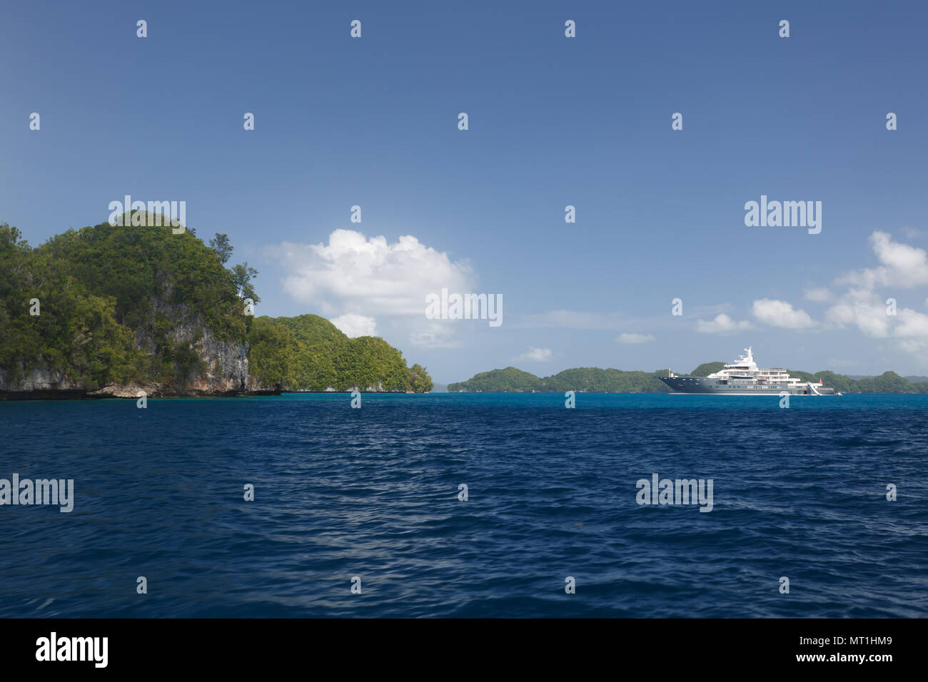 White mega yacht glides amid tropical islands in pacific Stock Photo