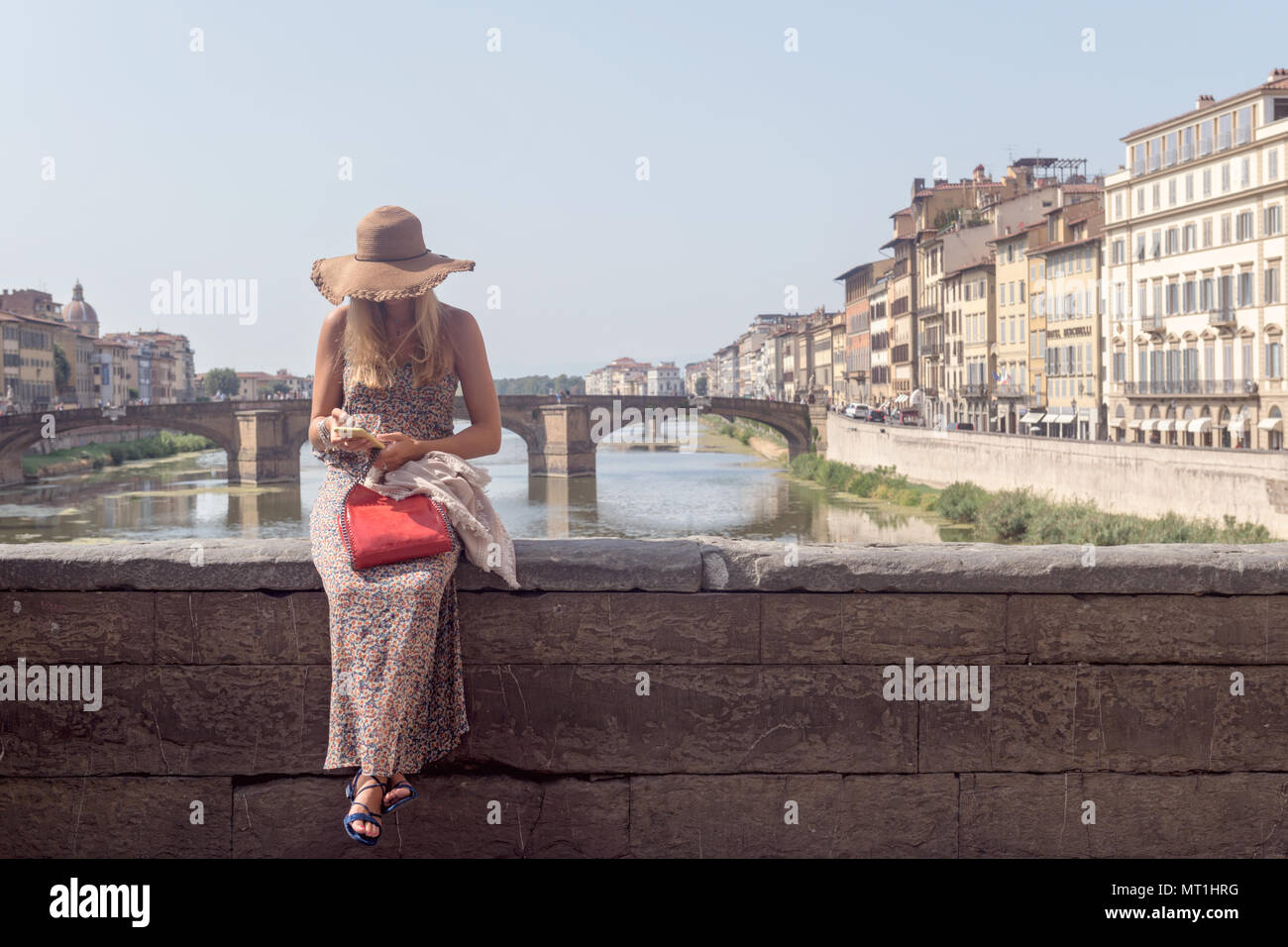 Young woman tourist using smart phone at Ponte Vecchio (Old Bridge) over the Arno River in Florence, Italy Stock Photo