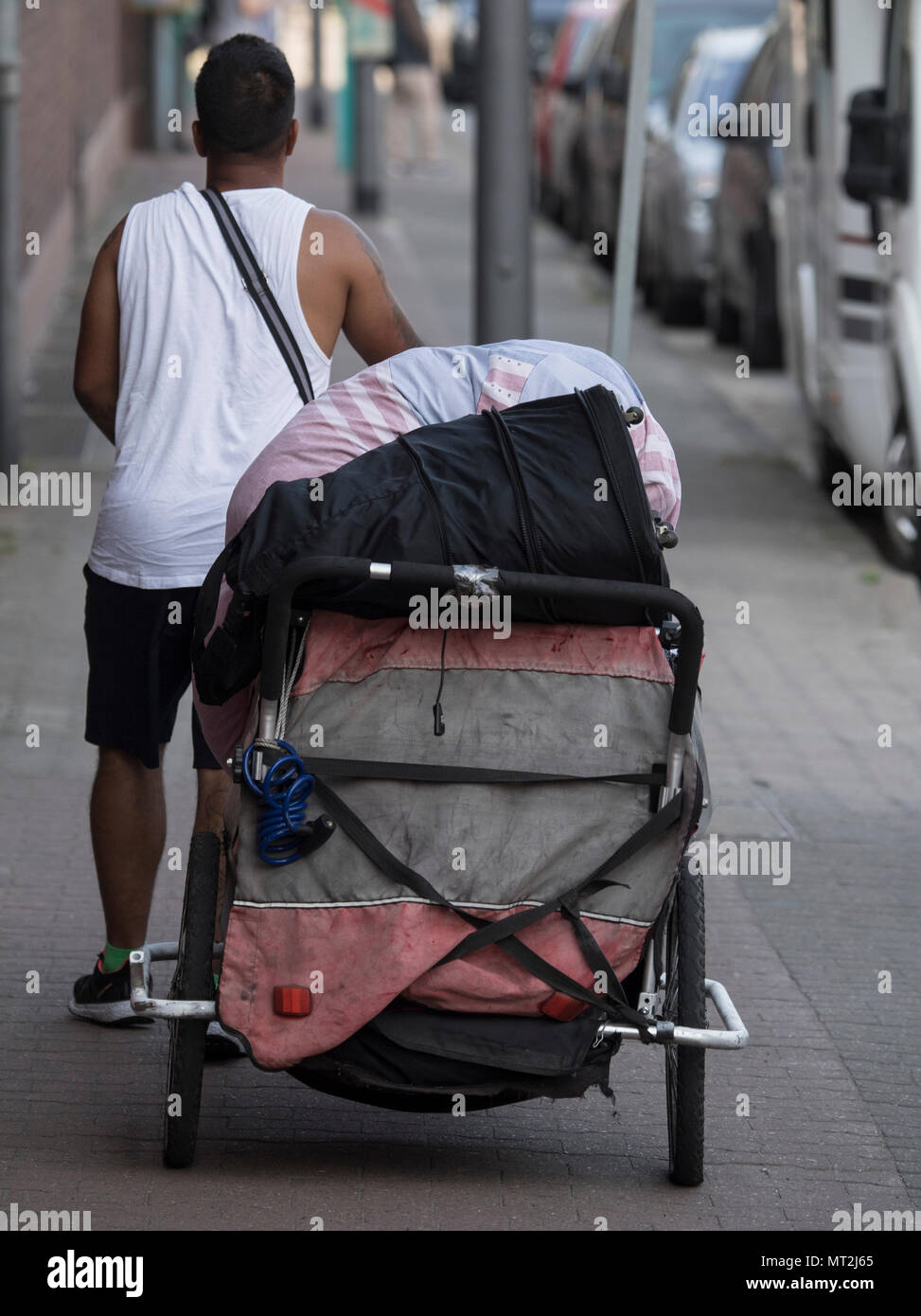 28 May 2018, Germany, Frankfurt am Main: A man with his belongings in a bicycle trailer crosses a road after leaving a homeless camp in the Gutleutviertel district. Police began clearing the homeless camp in the morning. Photo: Boris Roessler/dpa Stock Photo