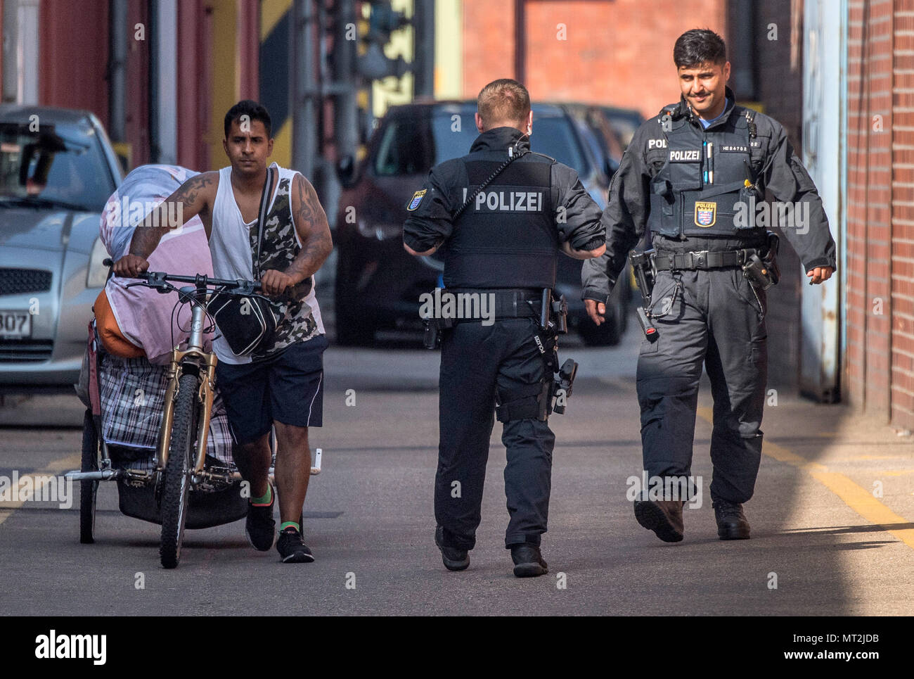 28 May 2018, Germany, Frankfurt am Main: Two police officers accompany a man across the site to a public street, as he leaves a homeless camp in the Gutleutviertel district. Police began clearing the camp in the morning. Photo: Boris Roessler/dpa Stock Photo