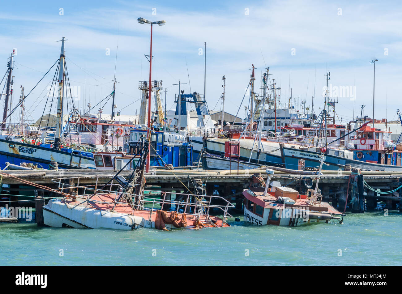 Luderitz, Namibia - July 08 2014: Luderitz harbor with many fishing boats and one sunken shipwreck Stock Photo