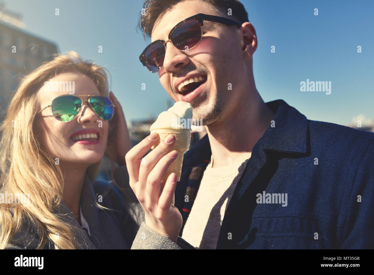 Happy romantic caucasian couple in sunglasses. Funny girl eat the ice cream Stock Photo