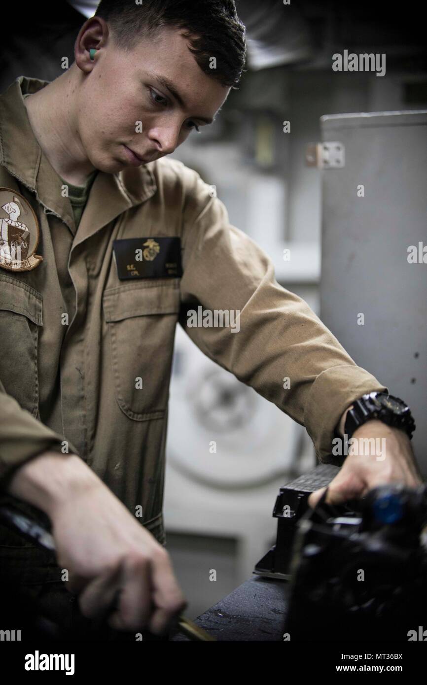 170722-N-UE100-0039 U.S. 5TH FLEET AREA OF OPERATIONS (July 22, 2017) Cpl. Spencer Bonds cleans the cooling coils of a heat exchanger for an MV-22B Osprey aboard the amphibious assault ship USS Bataan (LHD 5). The ship and its ready group are deployed in the U.S. 5th Fleet area of operations in support of maritime security operations to reassure allies and partners, and preserve the freedom of navigation and the free flow of commerce in the region. (U.S. Navy photo by Mass Communication Specialist 3rd Class Caleb Strong/Released) Stock Photo