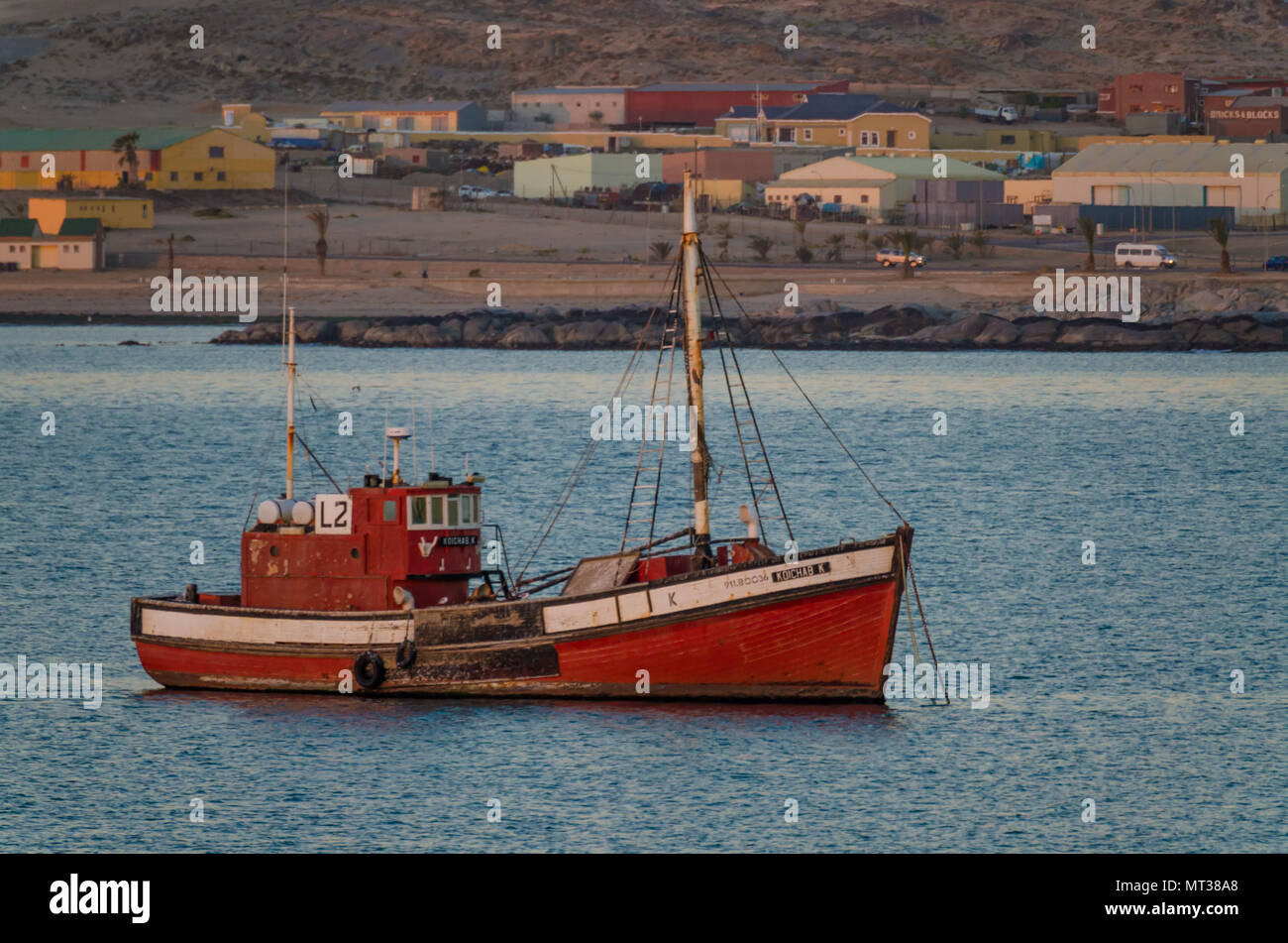 Luderitz, Namibia - July 09 2014: Old red wooden fishing boat in bay at Luderitz during evening Stock Photo