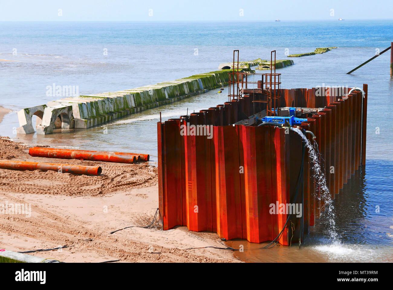 Water being pumped out of a cofferdam next to underwater pipe line construction Stock Photo