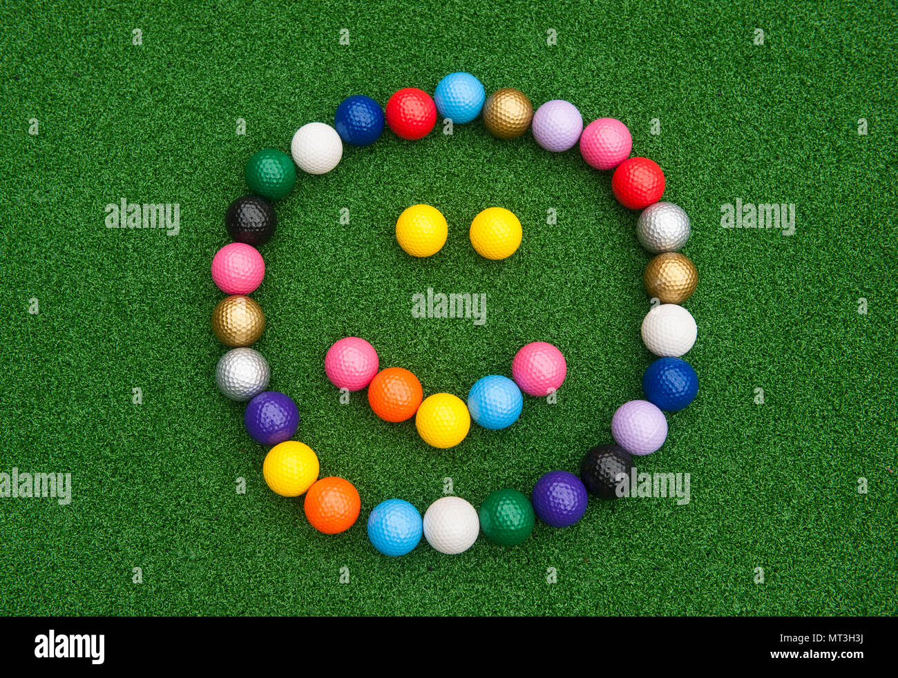 Happy face formed with colorful mini golf balls on artificial grass Stock Photo