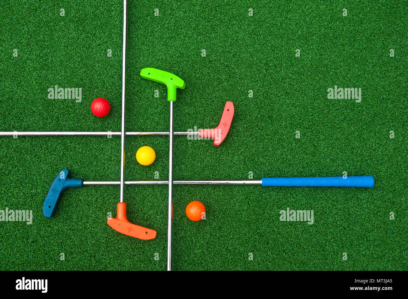 Criss Cross of colorful mini golf clubs and balls on artificial grass Stock Photo