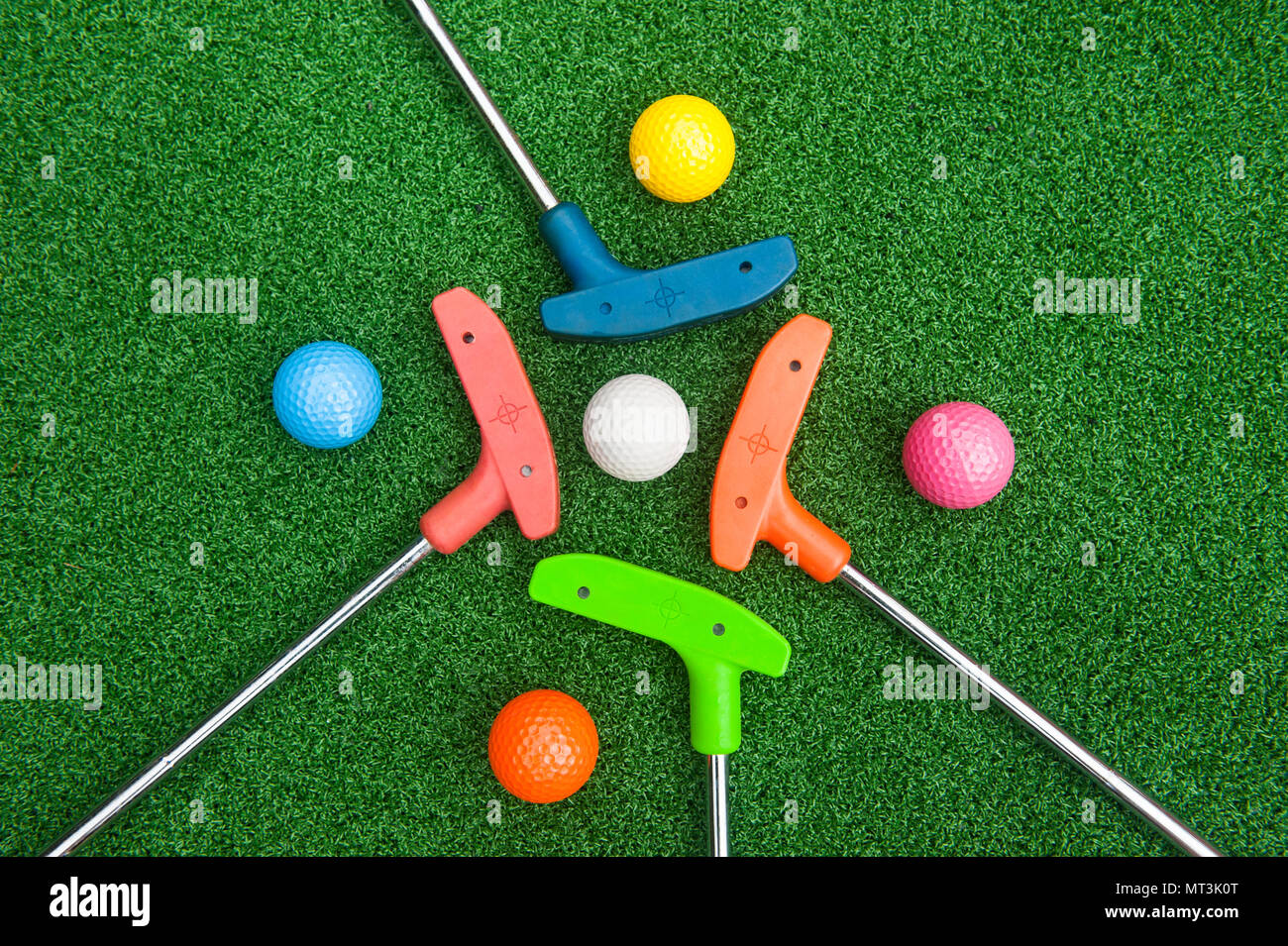 Four colorful golf putters with golf balls on synthetic grass Stock Photo