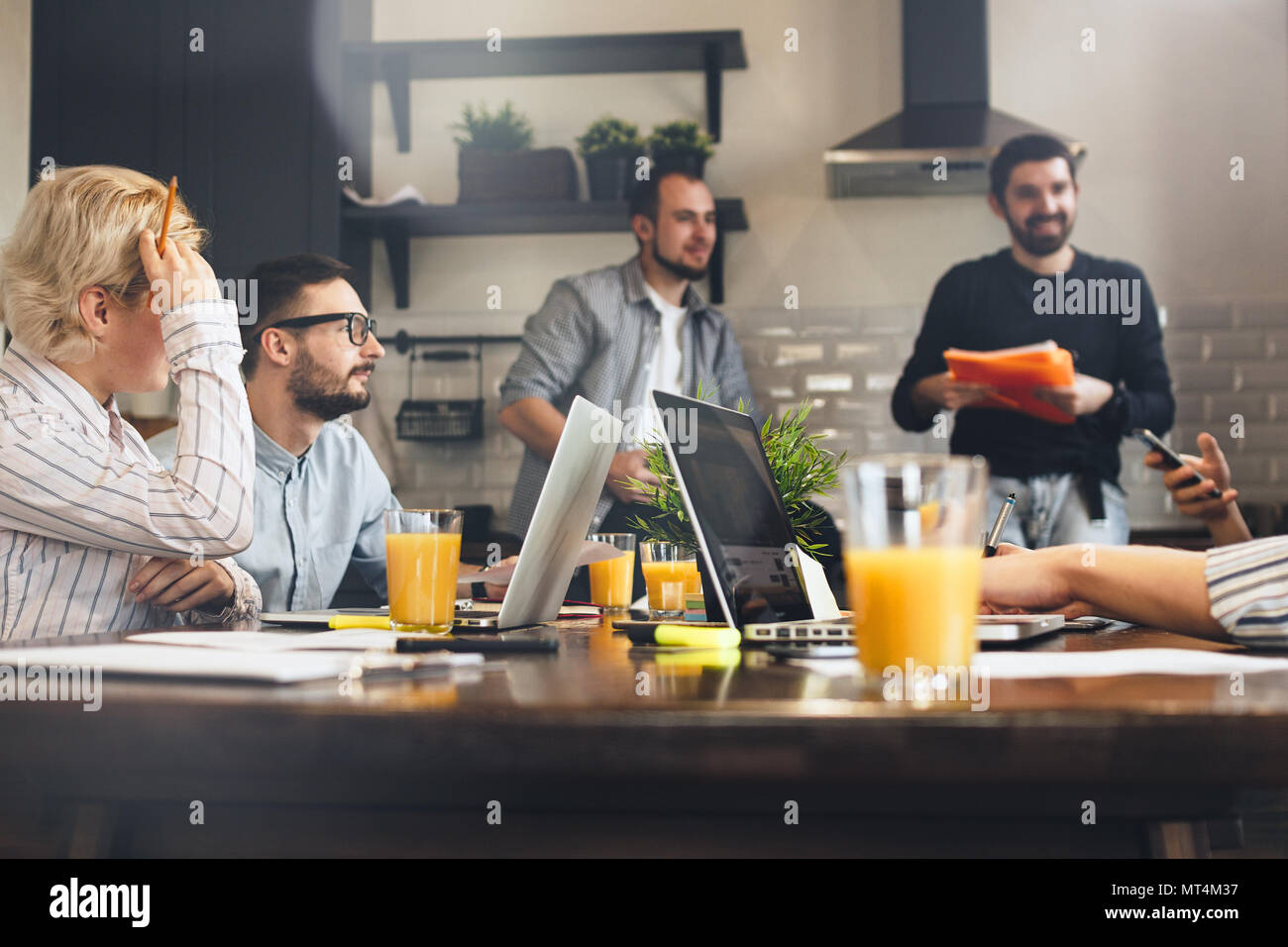 Group of creative coworkers brainstorming at kitchen. Business people working together and using laptops. Young team of managers making great business Stock Photo