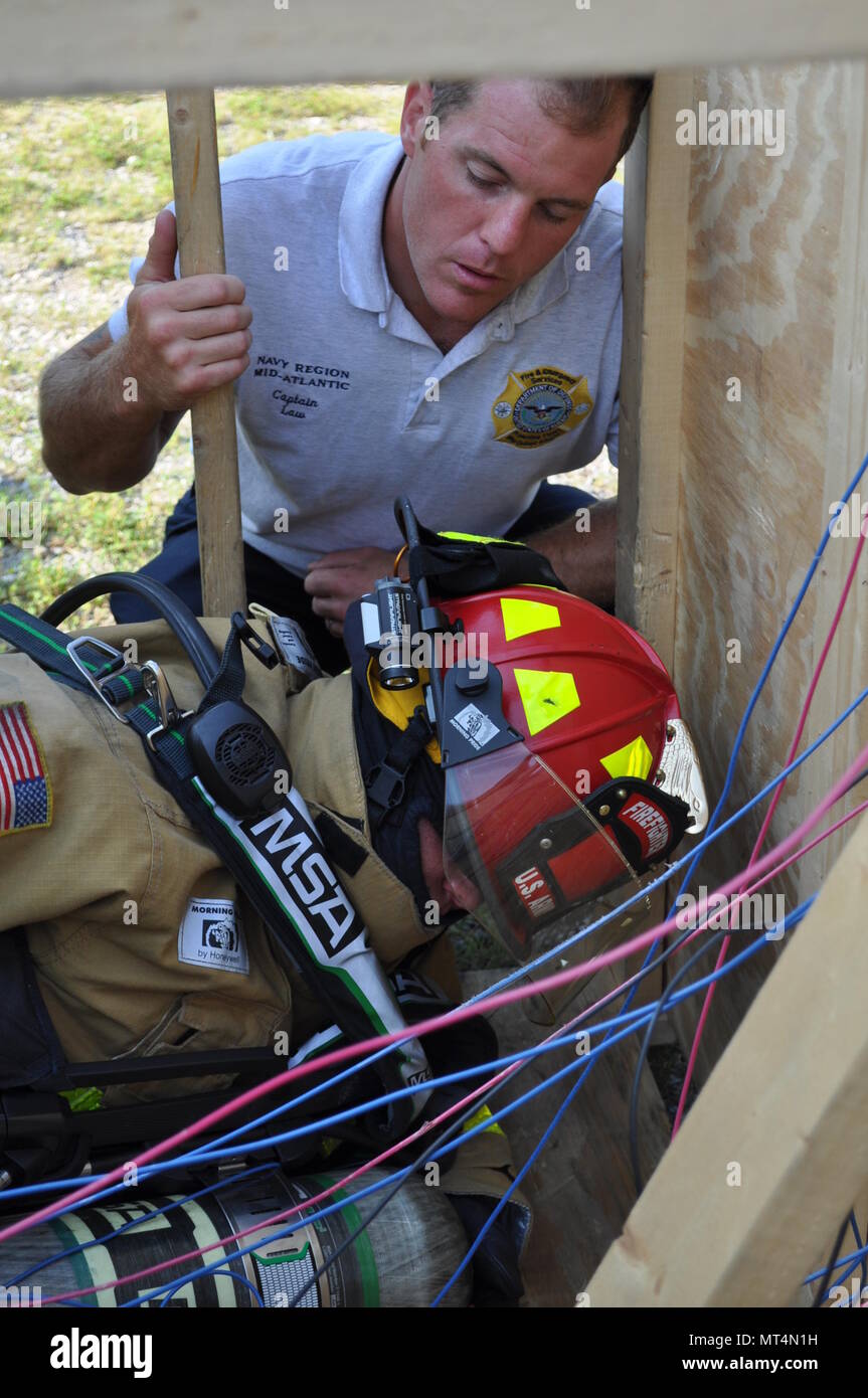 A Naval Support Activity Crane firefighter coaches a Soldier from the 802nd Ordnance Co. through a training exercise at Crane Army Ammunition Activity. The exercise involves simulations of real-life situations, such as navigating through confined spaces and tangled electrical wiring with a limited field of vision. The Soldiers are conducting their two-week annual training at Crane receiving hands-on education in ammunition handling, mechanics and firefighting skills. Stock Photo