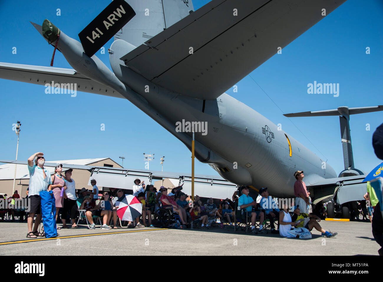 Service members and members from the local community sit under a KC-135 Stratotanker as they watch the performers perform during the SkyFest 2017 Air Show and Open House at Fairchild Air Force Base, Washington, July 29, 2017. SkyFest was an opportunity to give the local and regional community a chance to view Airmen and our resources. (U.S. Air Force photo/Senior Airman Janelle Patiño) Stock Photo