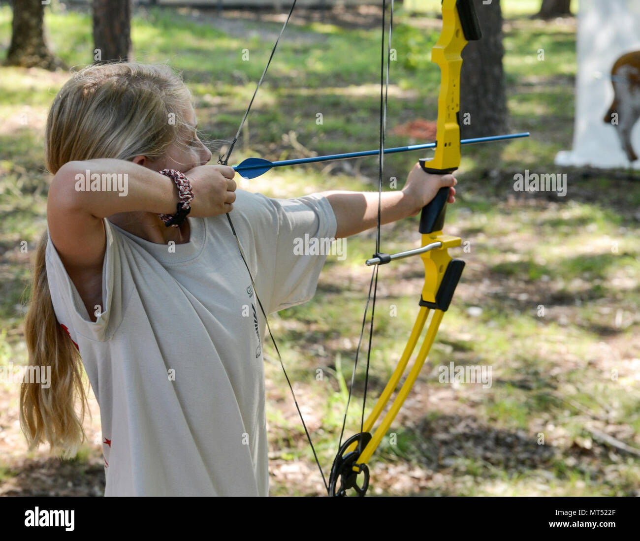 A camper aims a compound bow at targets during archery practice at the