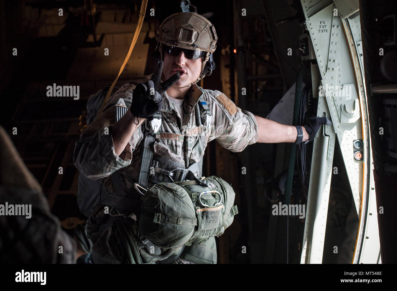 Tech. Sgt. Seth Sarrett, 374th Operations Support Squadron survival, evasion, resistance and escape specialist, gives a command prior to personnel jumping out of a C-130J Super Hercules over Yokota Air Base, Japan, July 28, 2017. Yokota SERE specialists conduct regular jump training to stay qualified and mission ready. (U.S. Air Force photo by Yasuo Osakabe) Stock Photo