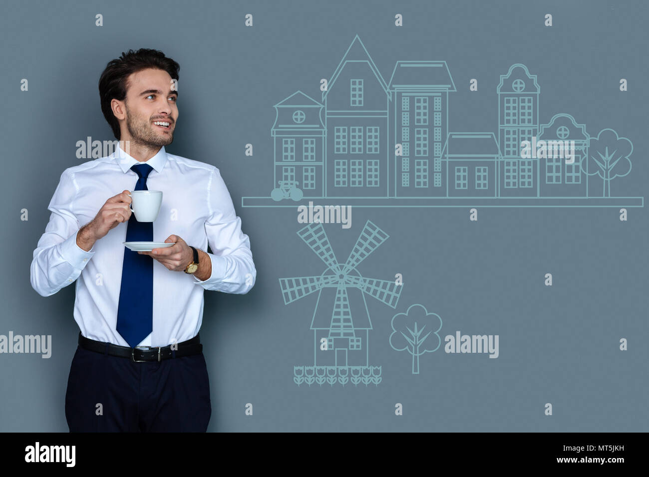 Calm man looking at the beautiful houses while drinking coffee Stock Photo