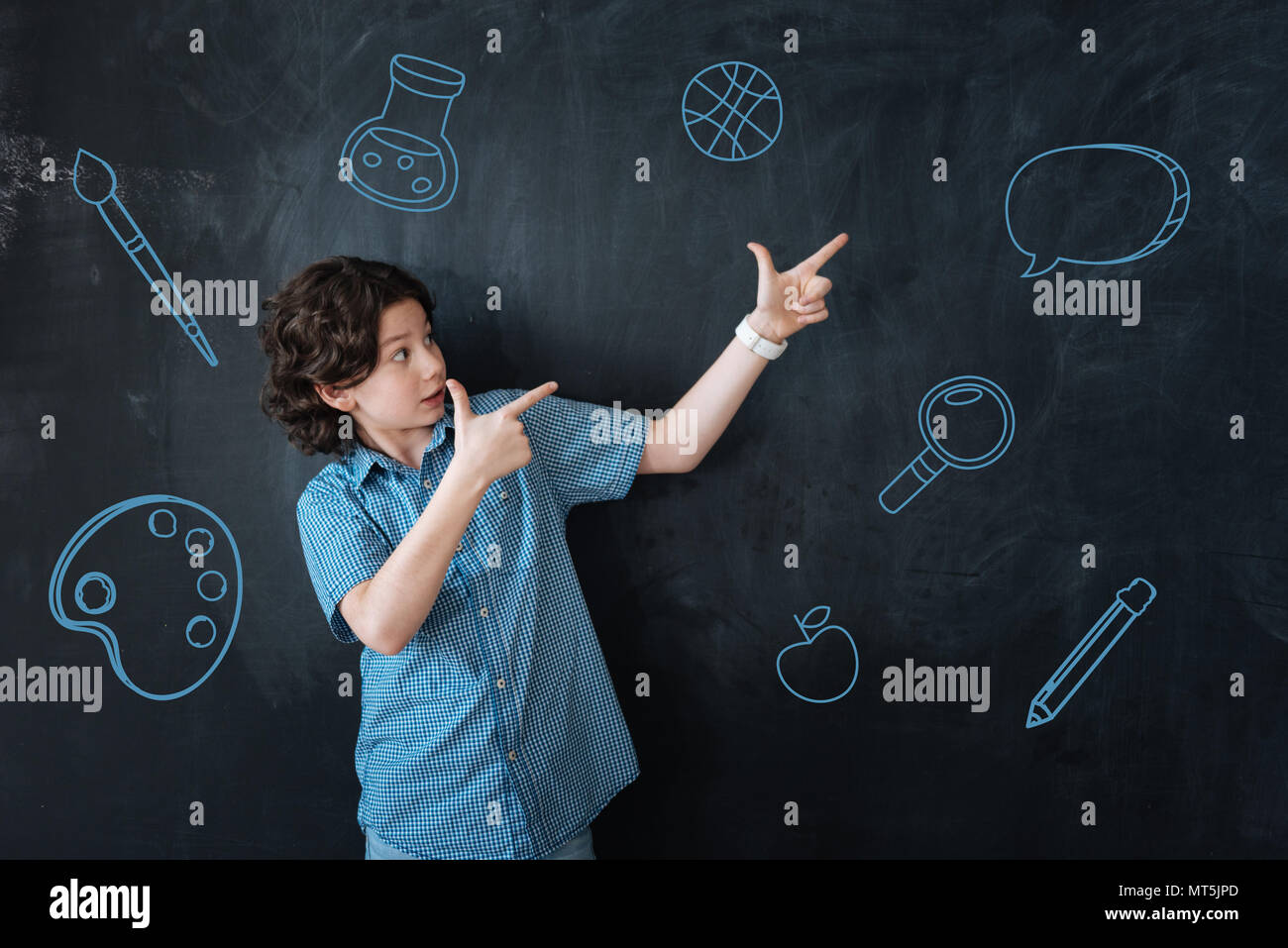 Emotional boy pointing to the wall while being at school Stock Photo