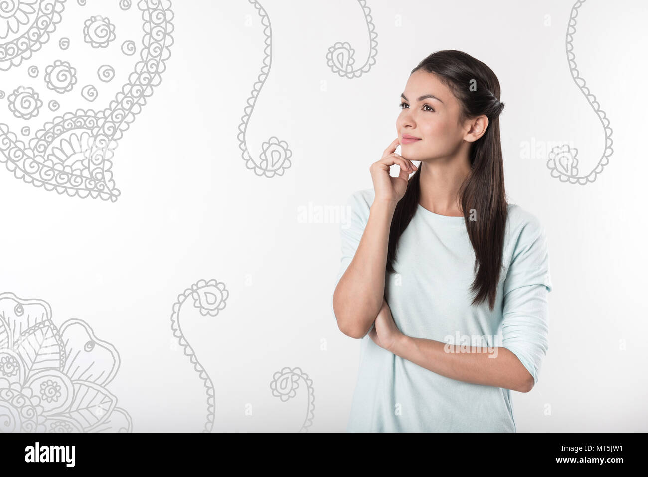 Dreamy young person smiling and looking at the ornaments on the wall Stock Photo