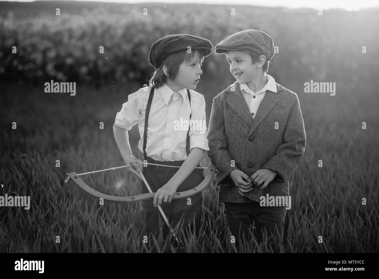 Portrait of children playing with bow and arrows, archery shoots a bow at the target on sunset Stock Photo