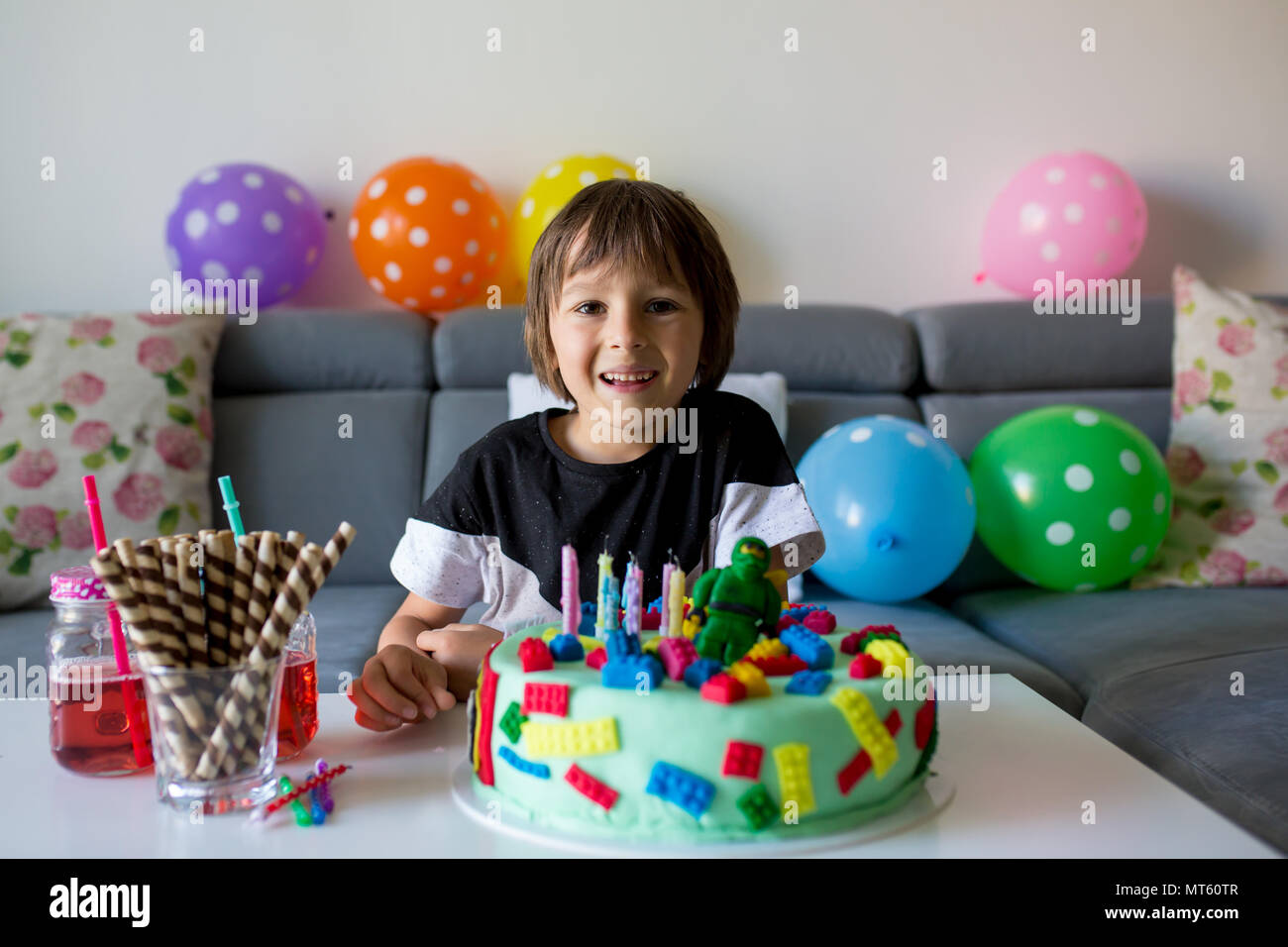 Cute child, boy, celebrating his birthday with colorful cake, candles, balloons at home Stock Photo