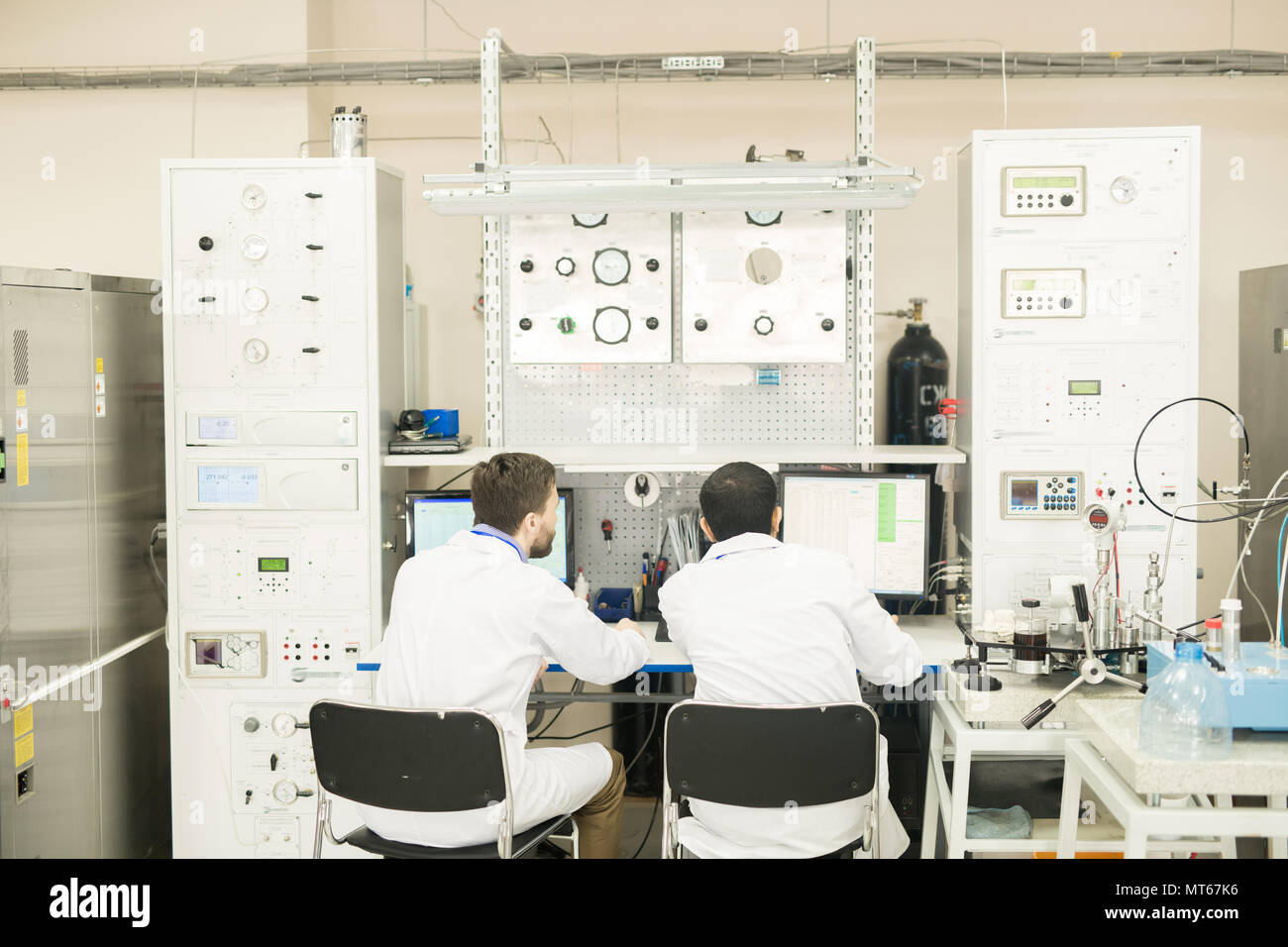 Engineers working with computer connected to control cabinet Stock Photo