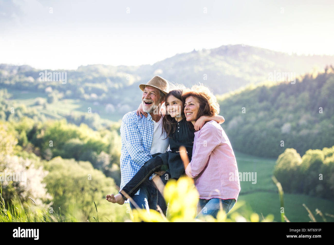 Senior couple with grandaughter outside in spring nature, relaxing and having fun. Stock Photo