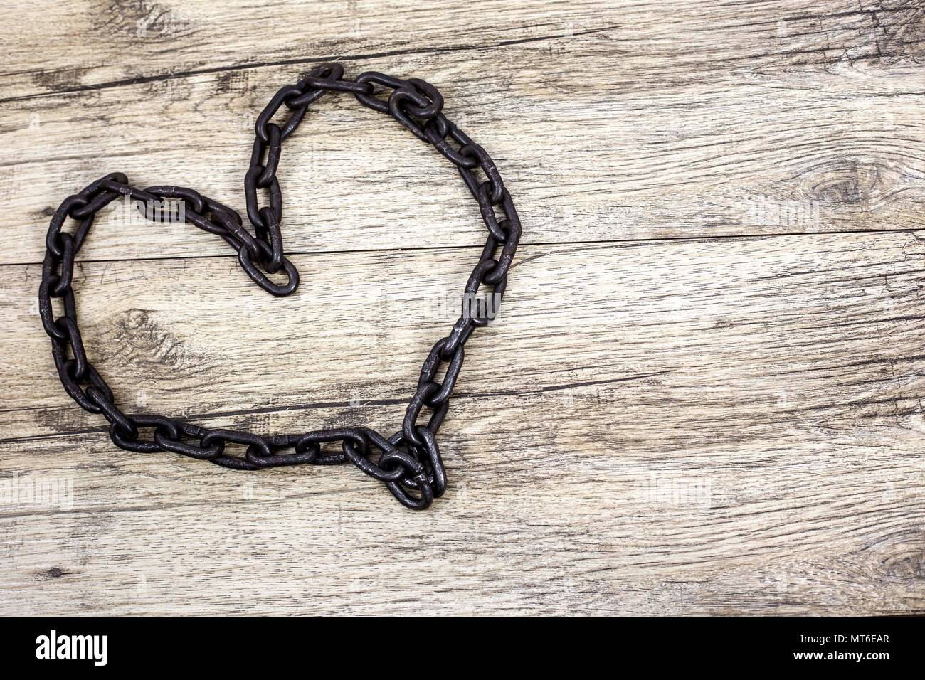 Rusty chain heart shape on wooden background Stock Photo