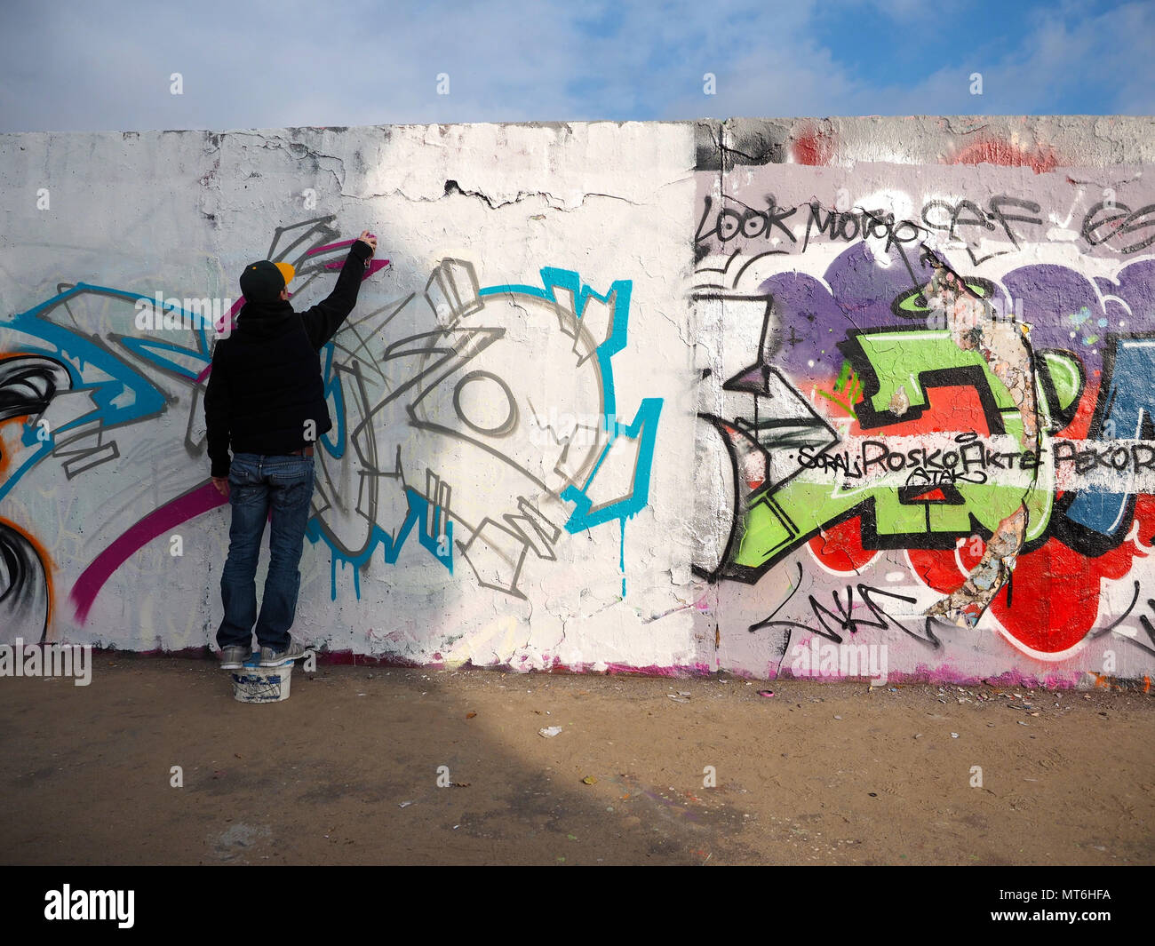 man painting graffiti on Berlin wall Stock Photo