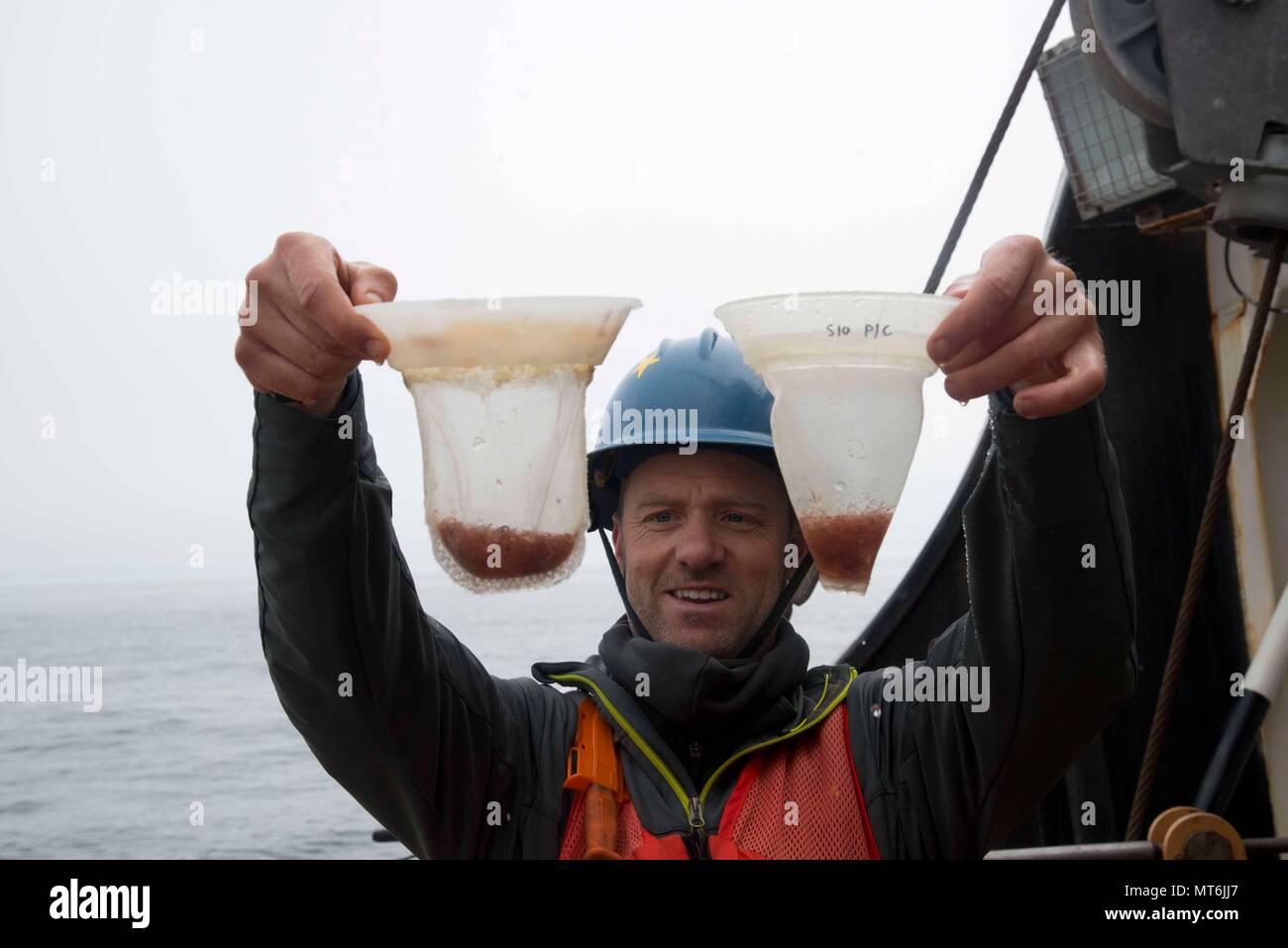 Josh Jones, a graduate student researcher at the Scripps Institution of Oceanography in San Diego, California, holds up samples of zooplankton aboard Coast Guard Cutter Maple in the Arctic Ocean east of Barrow, Alaska, July 26, 2017. The crew of the 225-foot buoy tender out of Sitka is working to support Jones' marine mammal research. (U.S. Coast Guard photo by Petty Officer 2nd Class Nate Littlejohn/Released) Stock Photo
