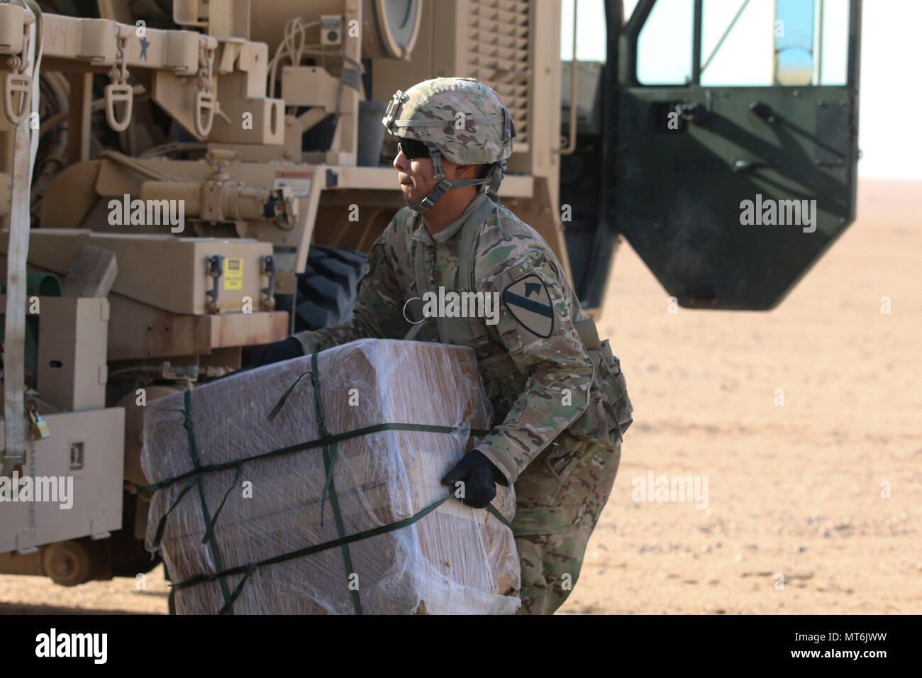 A Soldier assigned to 215th Brigade Support Battalion, 3rd Armored Brigade Combat Team, 1st Cavalry Division recovers one of two bundles off of the drop zone during air drop resupply training July 27, 2017 at Udairi Range Complex, Kuwait. The Soldiers were evaluated on their execution of a tactical convoy, drop zone set-up and marking, drop zone security, and resupply recovery. (U.S. Army photo by Staff Sgt. Leah R. Kilpatrick)) Stock Photo