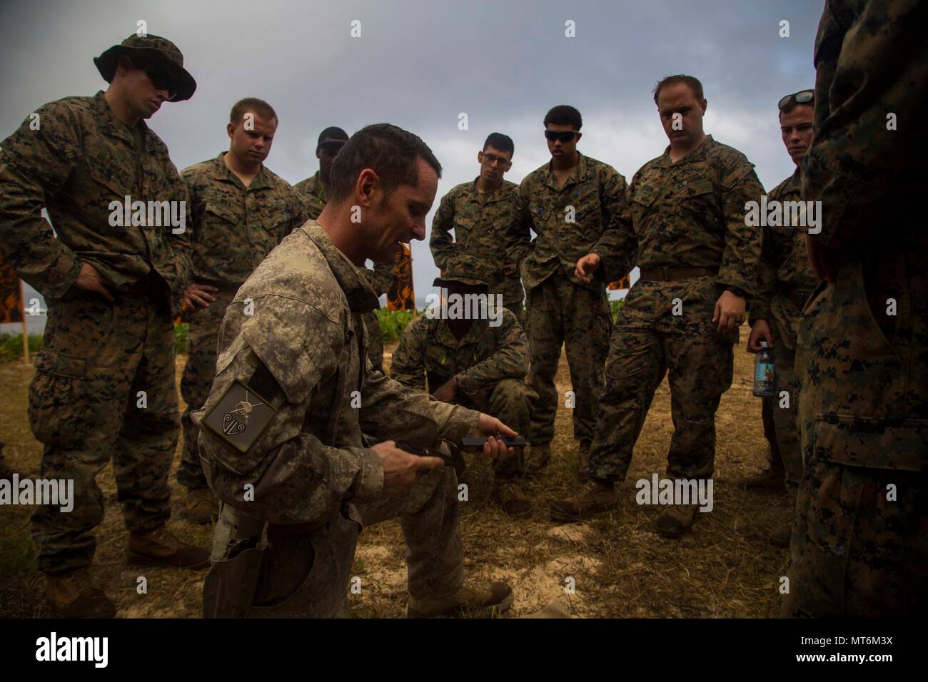 U.S. Marines with 3rd Battalion 4th Marines attached to Task Force Koa Moana 17, gather around New Zealand Army Sgt. Maj. Paul Buckley as he explains the glock 17 weapon system during Exercise TAFAKULA, on Tongatapu Island, Tonga, July 21, 2017. Exercise TAFAKULA is designed to strengthen the military-to-military, and community relations between Tonga’s His Majesty’s Armed Forces, French Army of New Caledonia, New Zealand Defense Force, and the United States Armed Forces. (U.S. Marine Corps photo by MCIPAC Combat Camera Lance Cpl. Juan C. Bustos) Stock Photo