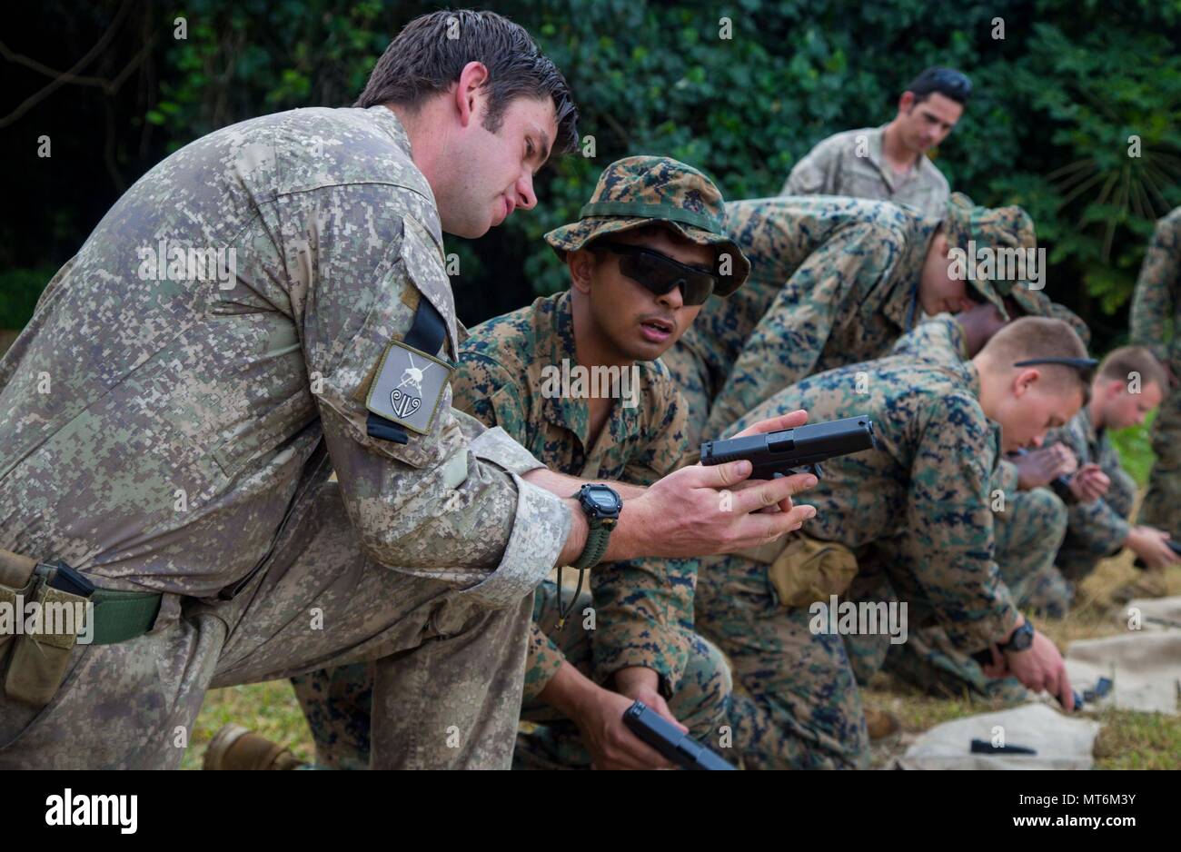 A New Zealand Army soldier shows U.S. Marine Corps Lance Cpl. Christian Damian, a rifleman with 3rd Battalion 4th Marines attached to Task Force Koa Moana 17, how to activate the safety of a glock 17 weapon system during Exercise TAFAKULA, on Tongatapu Island, Tonga, July 21, 2017. Exercise TAFAKULA is designed to strengthen the military-to-military, and community relations between Tonga’s His Majesty’s Armed Forces, French Army of New Caledonia, New Zealand Defense Force, and the United States Armed Forces.  (U.S. Marine Corps photo by MCIPAC Combat Camera Lance Cpl. Juan C. Bustos) Stock Photo