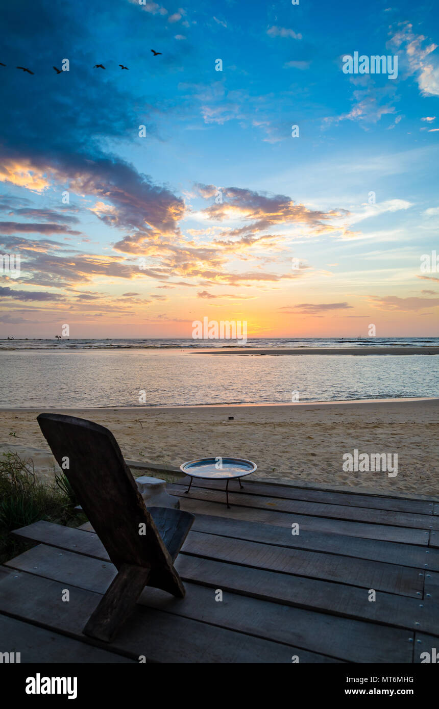 Traditional wooden African chair on terrasse at beach overlooking the ocean during beautiful sunset, Senegal, Africa Stock Photo