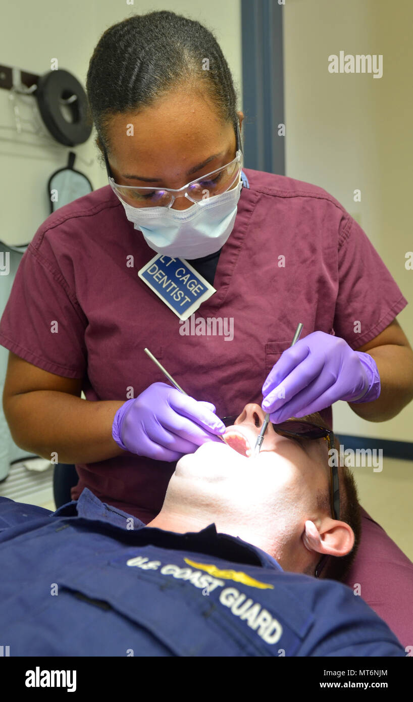 JACKSONVILLE, Fla. (July 12, 2017) – Lt. Charlie Cage, a dentist at Naval Branch Health Clinic Jacksonville, conducts an annual exam on Coast Guard Avionics Electrical Technician 2nd Class James Mann. The Dental Corps was established in 1912, and a few years later, had an immediate impact during World War I. (U.S. Navy photo by Jacob Sippel, Naval Hospital Jacksonville Public Affairs/Released). Stock Photo