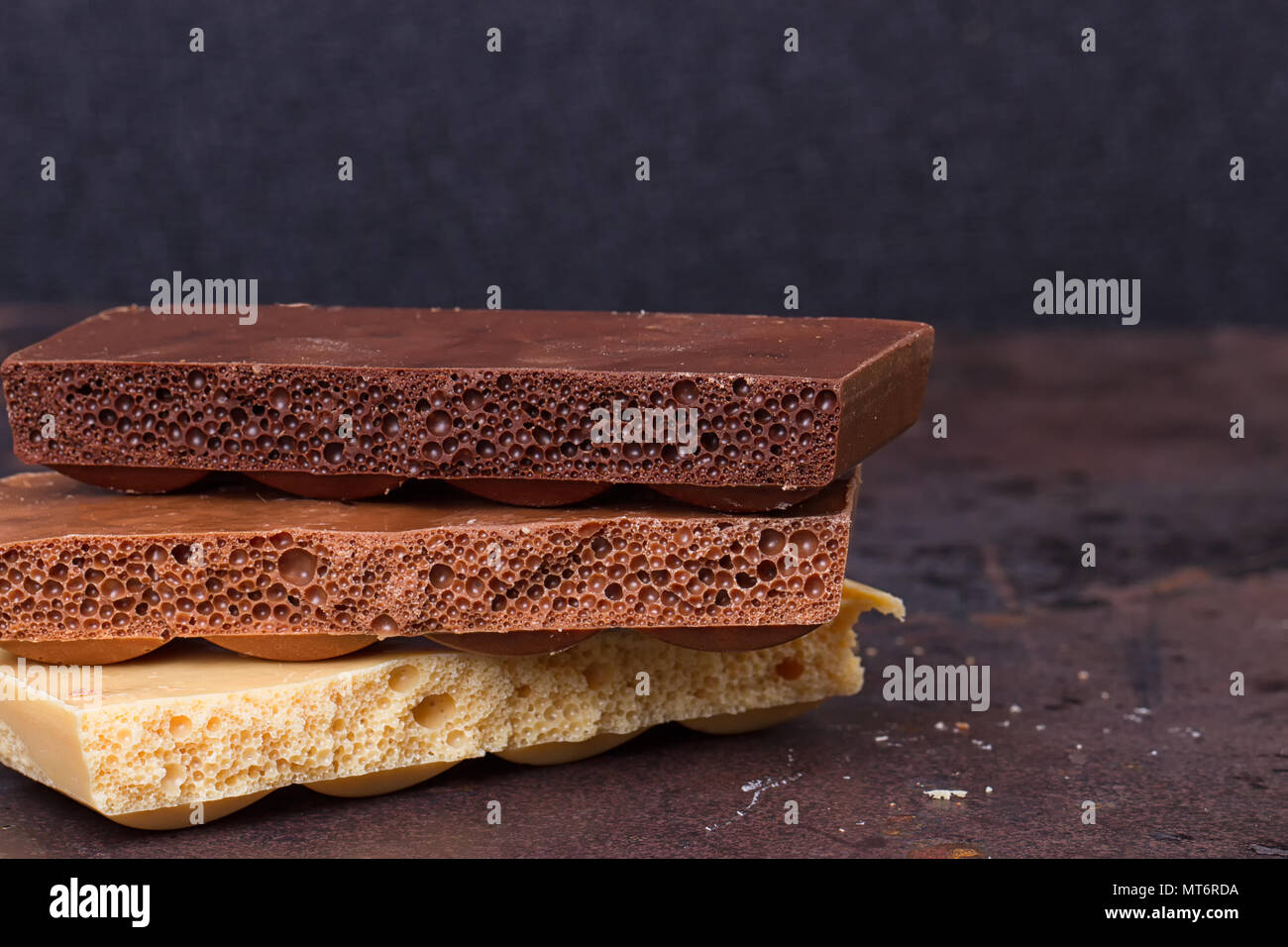 Chocolate Polymorphs Stacking Pattern stack of different kind porous chocolate pieces on a dark background ...