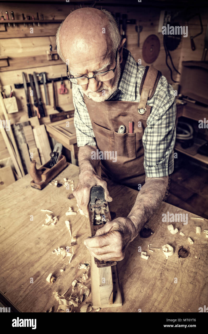 senior carpenter use handplaner in his workshop Stock Photo