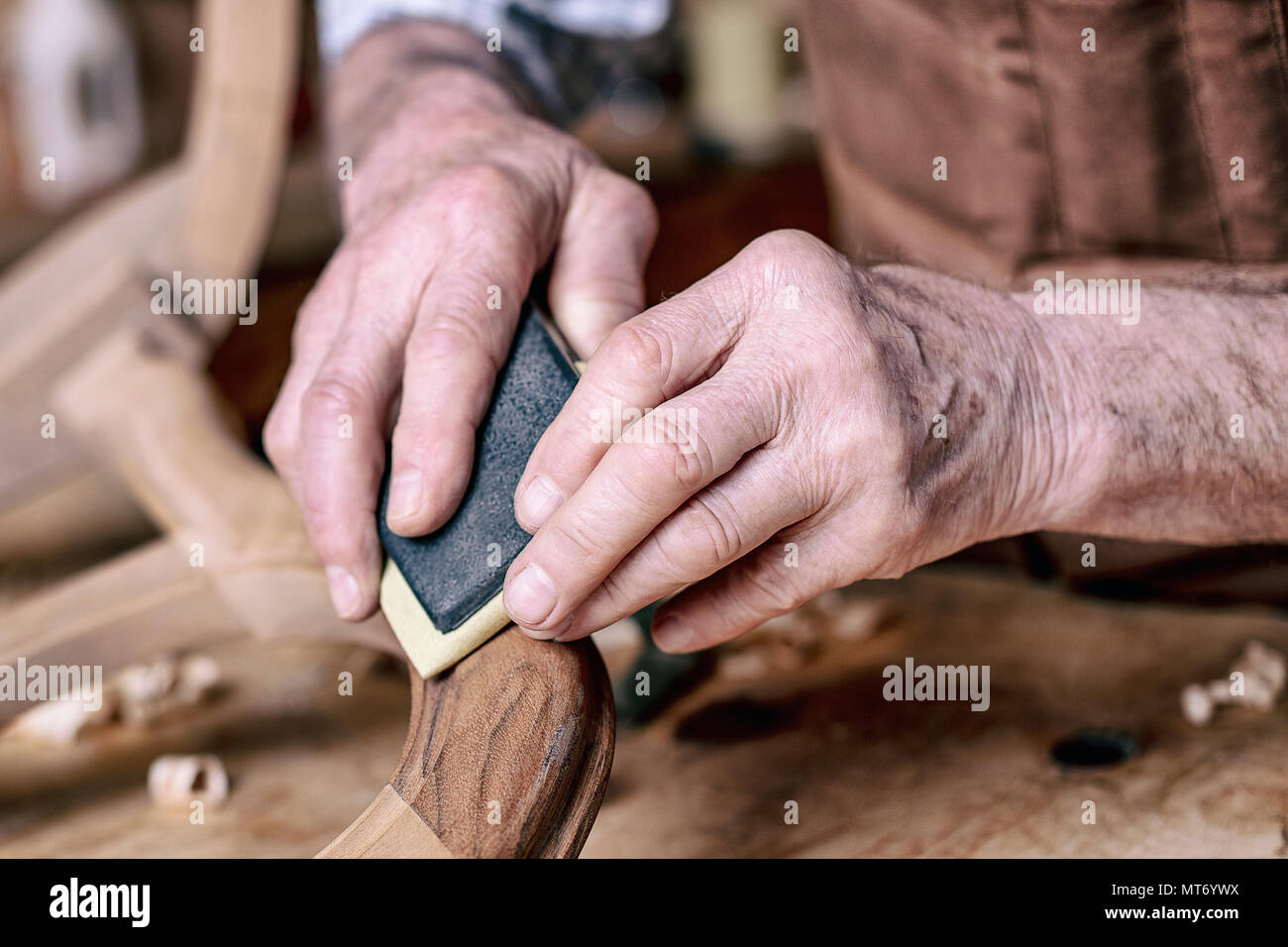 carpenter hands sanding unfinished chair Stock Photo