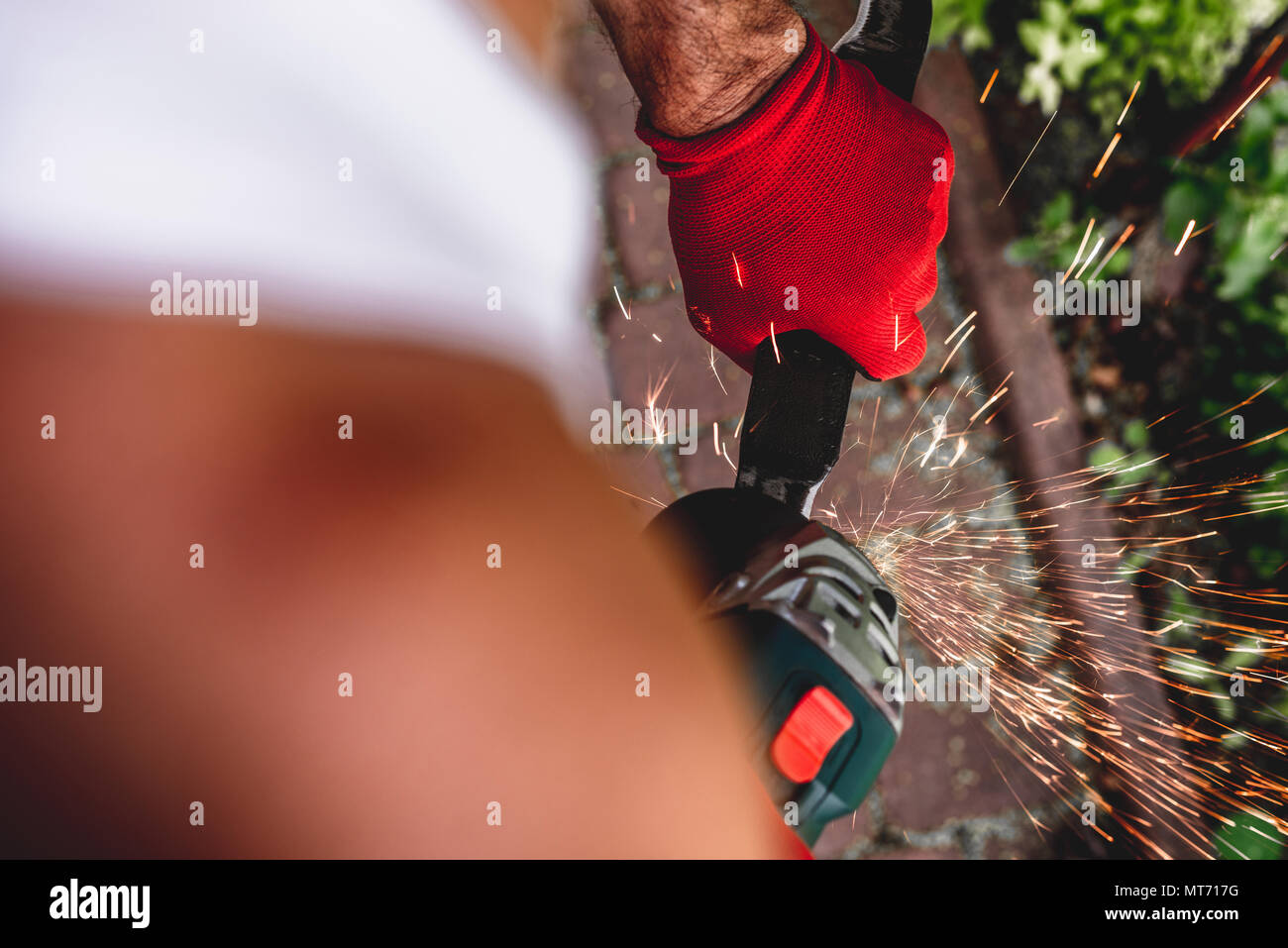 The man is sharp with the mower's knife with a grinder, sparks fly from