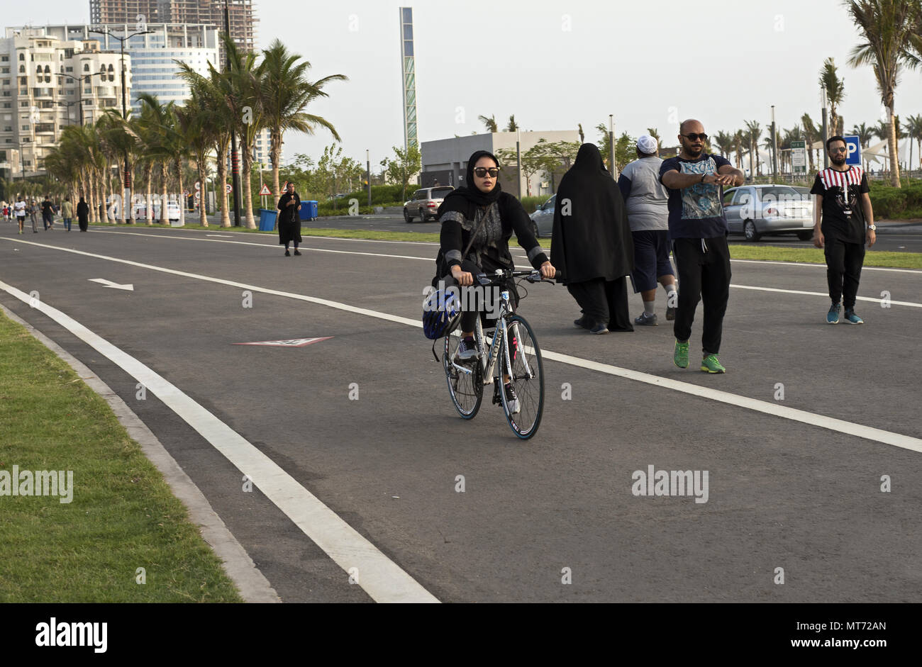 Saudi woman in black abaya riding a bicycle in Jeddah Saudi Arabia on the new running track in the Corniche Stock Photo