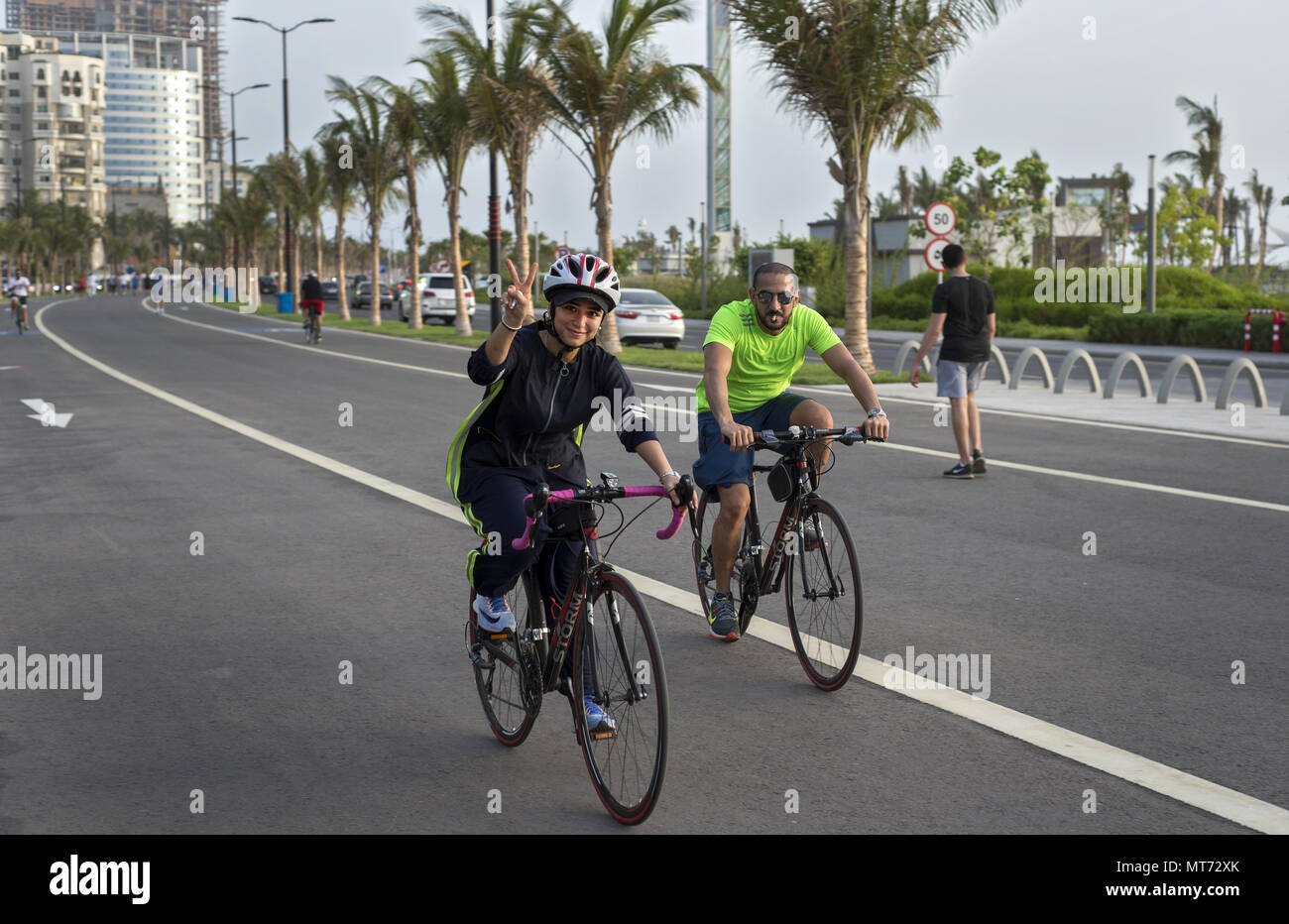 Saudi woman riding bicycle in Jeddah, Saudi Arabia in modern athletic abaya Stock Photo