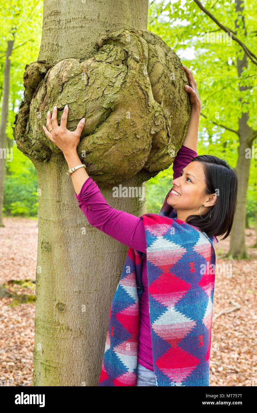 Colombian woman holding cancerous tumor on beech tree trunk Stock Photo