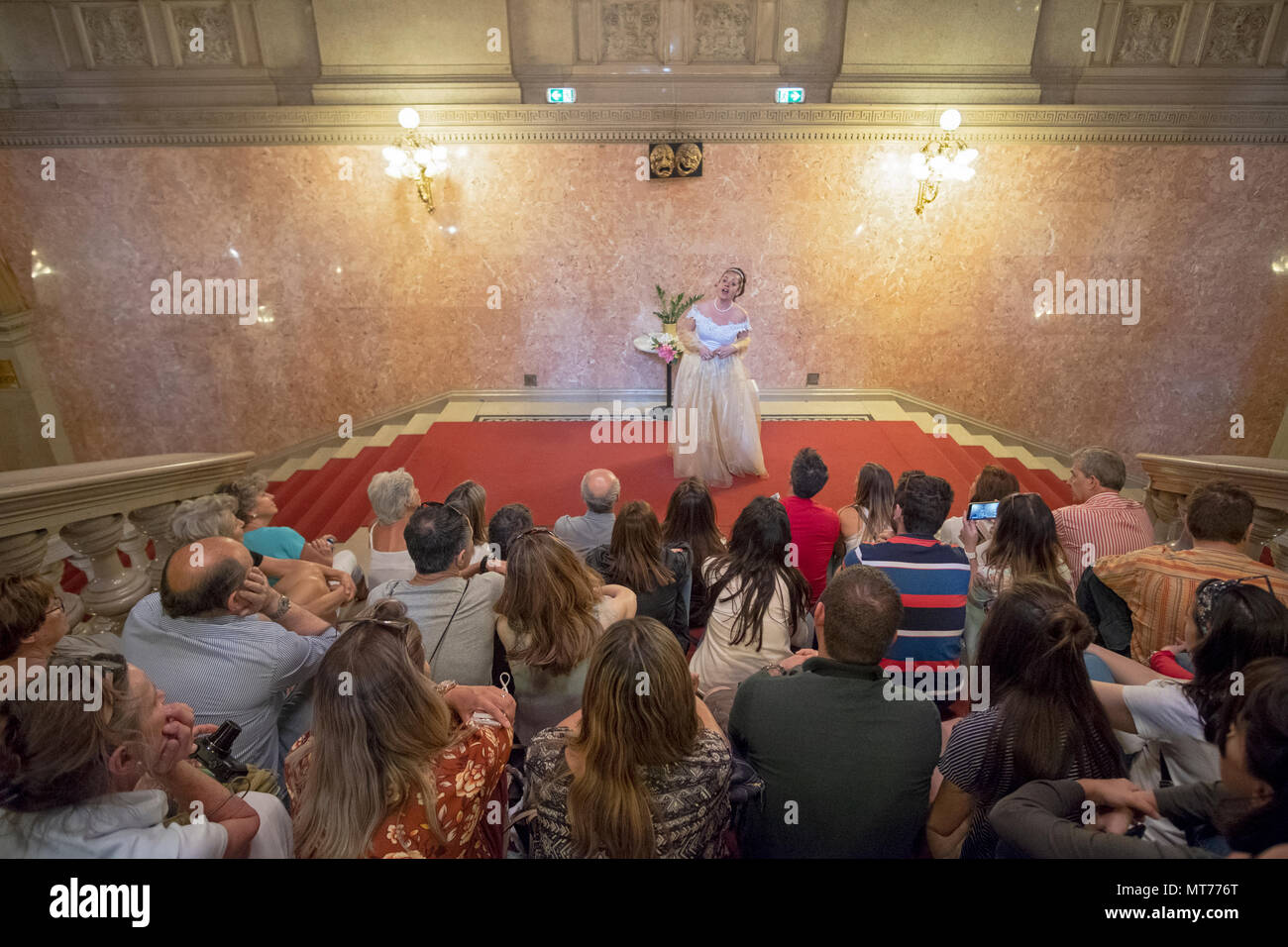 A gesturing opera singer performing for a group of Viking River Boat tourists at the Budapest Opera House in Budapest, Hungary. Stock Photo