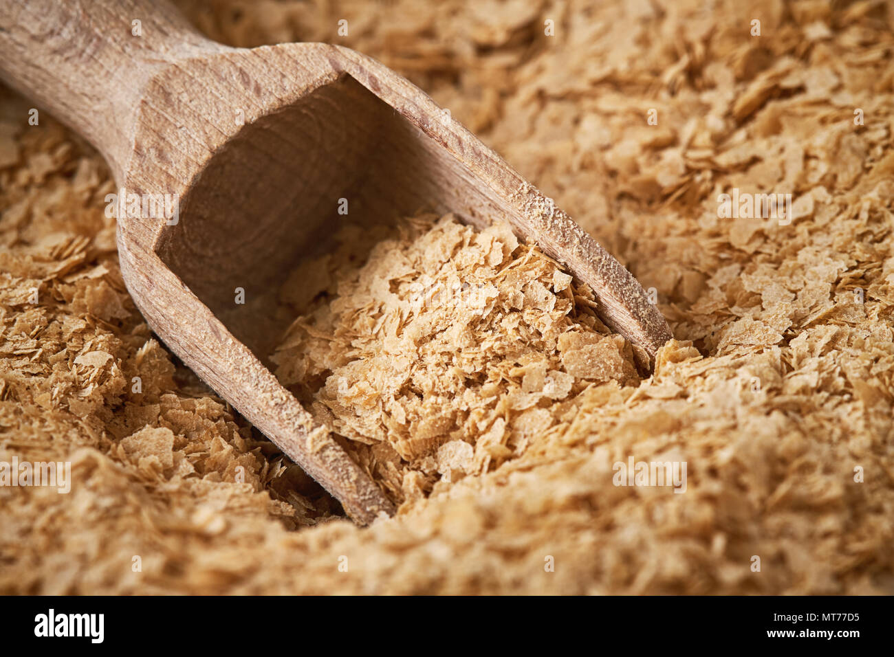 Closeup of nutritional brewers yeast flakes with wooden scoop Stock
