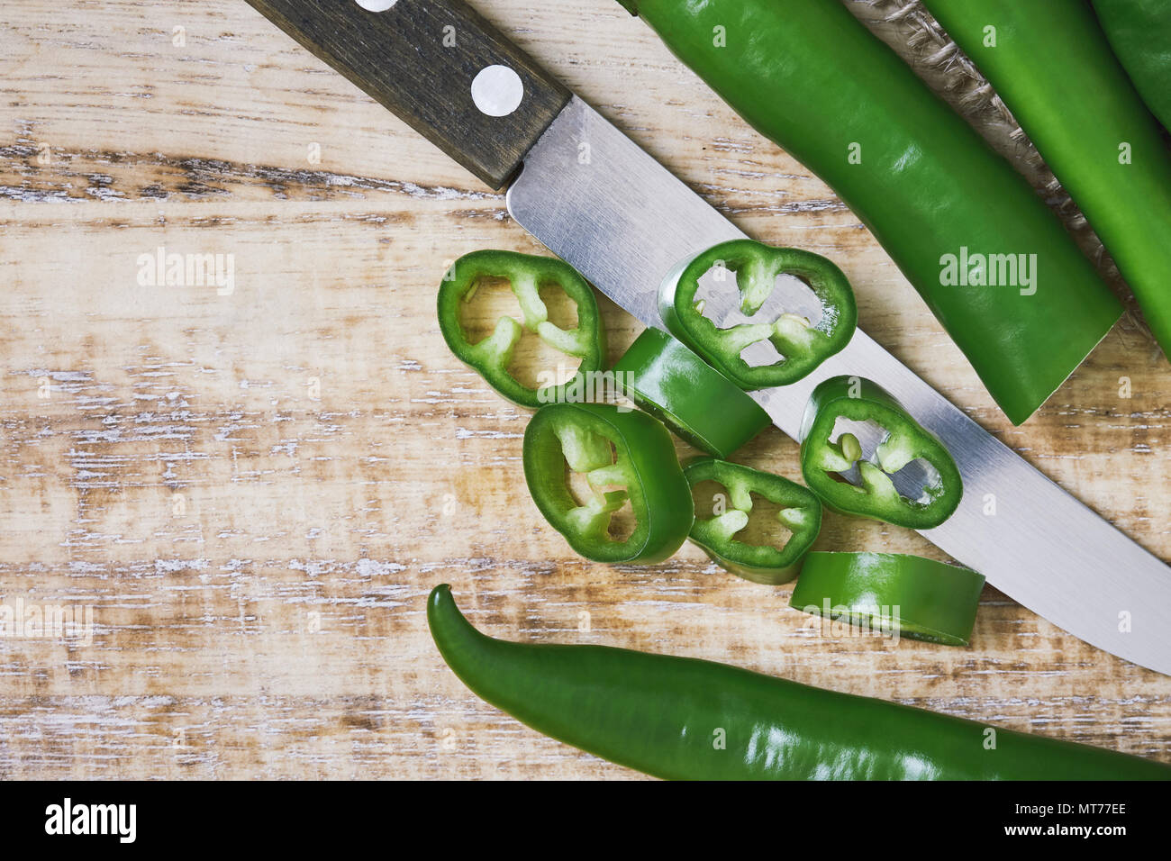 Fresh raw sliced green chili pepper on cutting board. Top view with ...