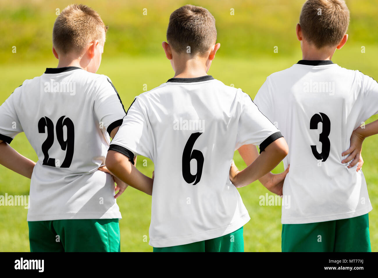 Children Sports Team Wearing White Soccer Jersey Shirts. Young Boys Watching Soccer Match. Football Tournament Competition in the Background. Kids Foo Stock Photo