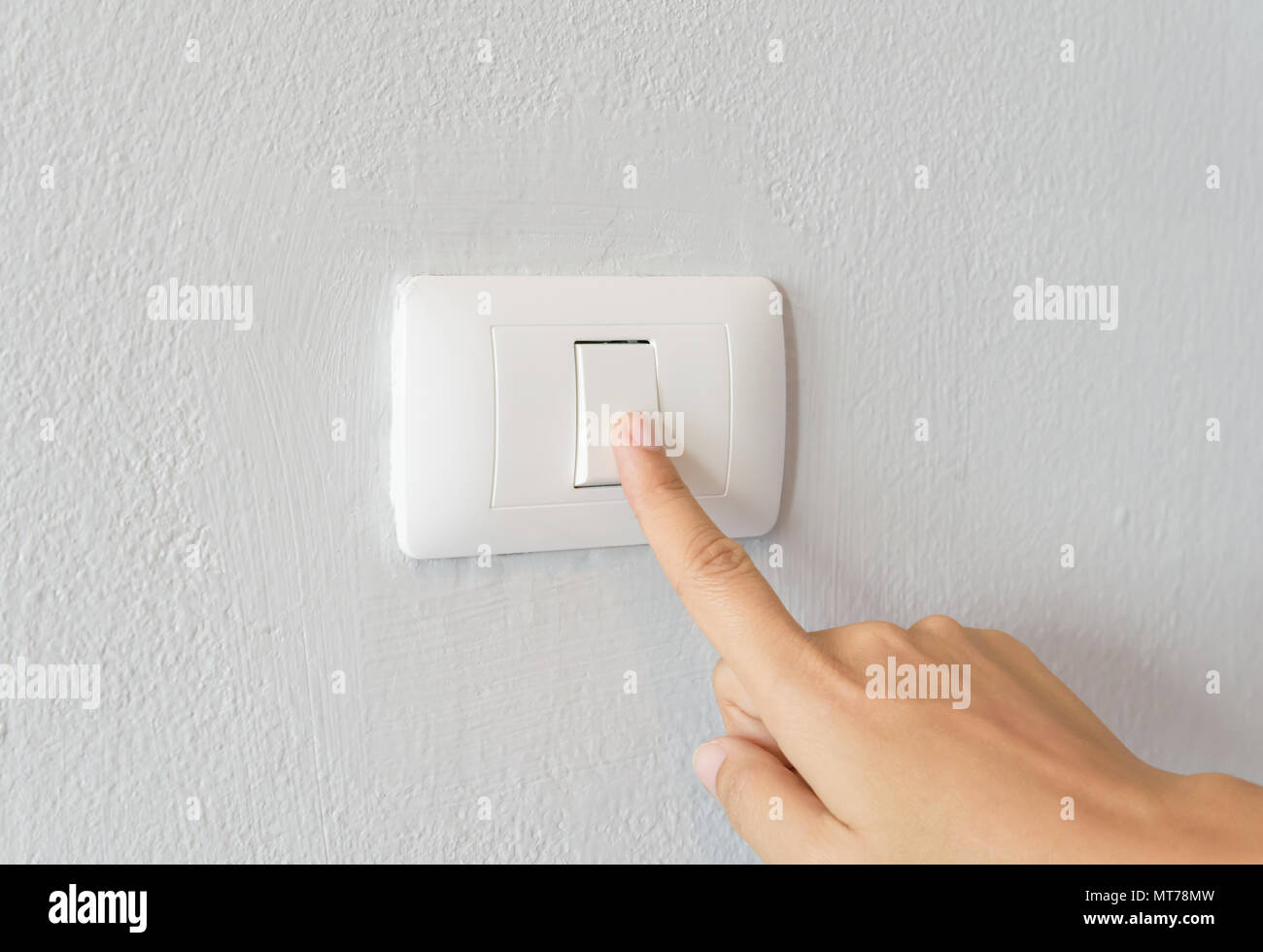 Close up of woman finger  turning on light switch with white background copy space. Stock Photo