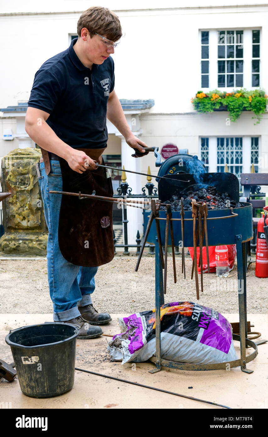 blacksmith working outdoors at the pantiles tunbridge wells heating iron in a fire Stock Photo